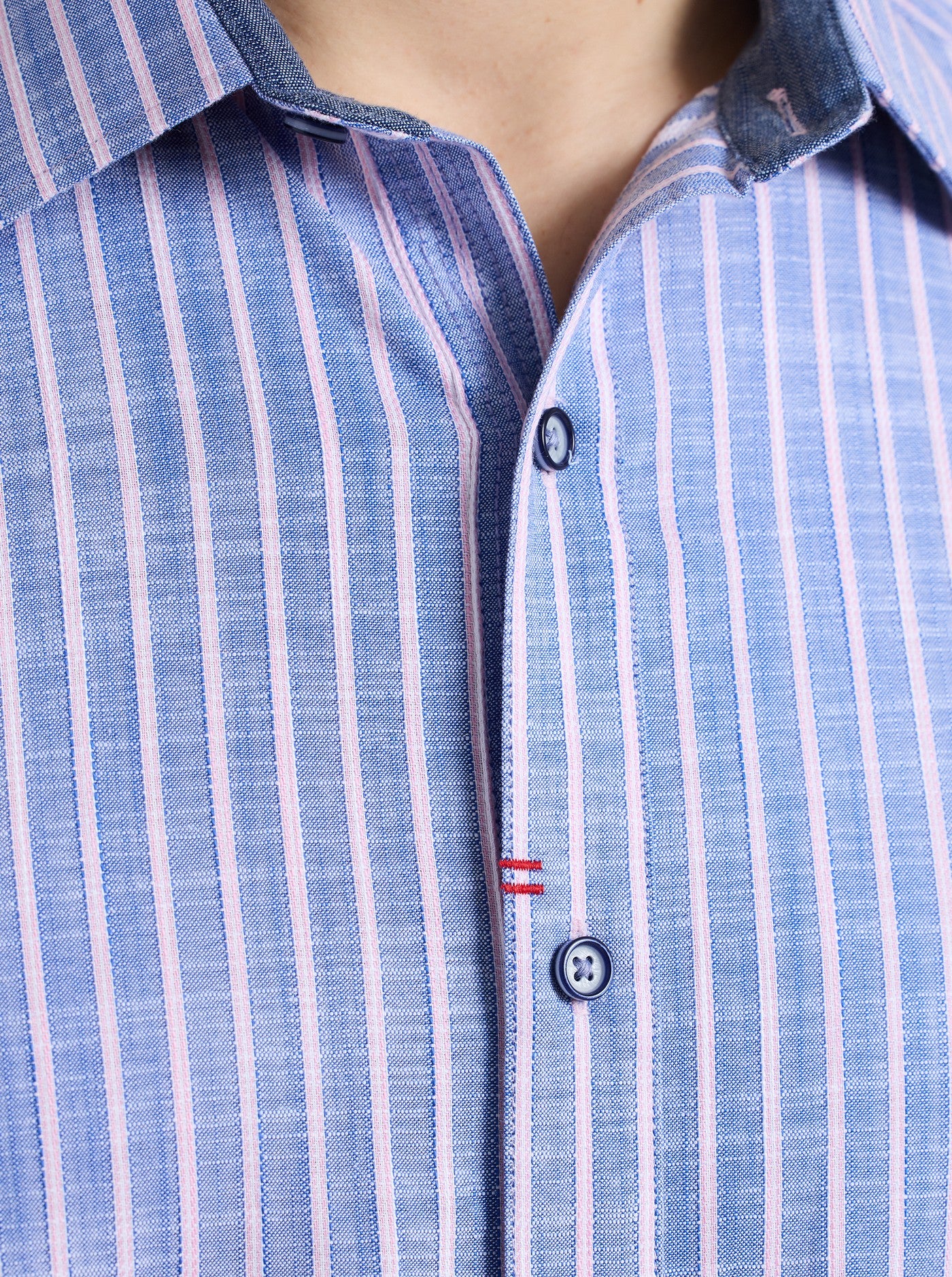 Close-up of a blue and white striped shirt with a button detail.