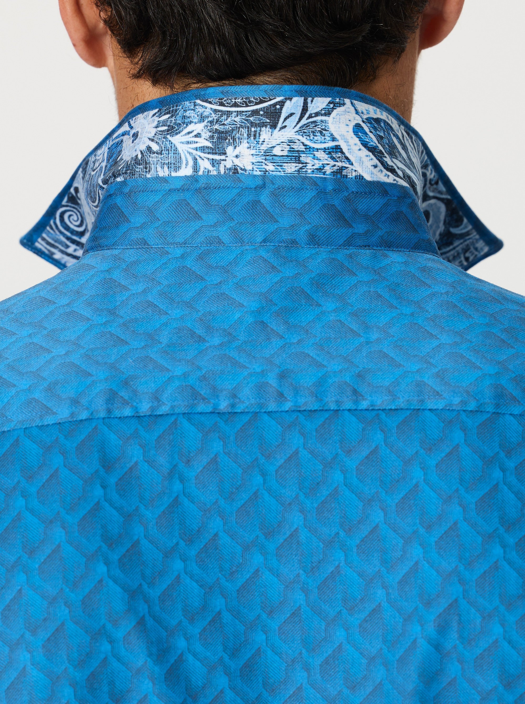 Blue geometric patterned shirt with a contrast floral decorative collar on a white background