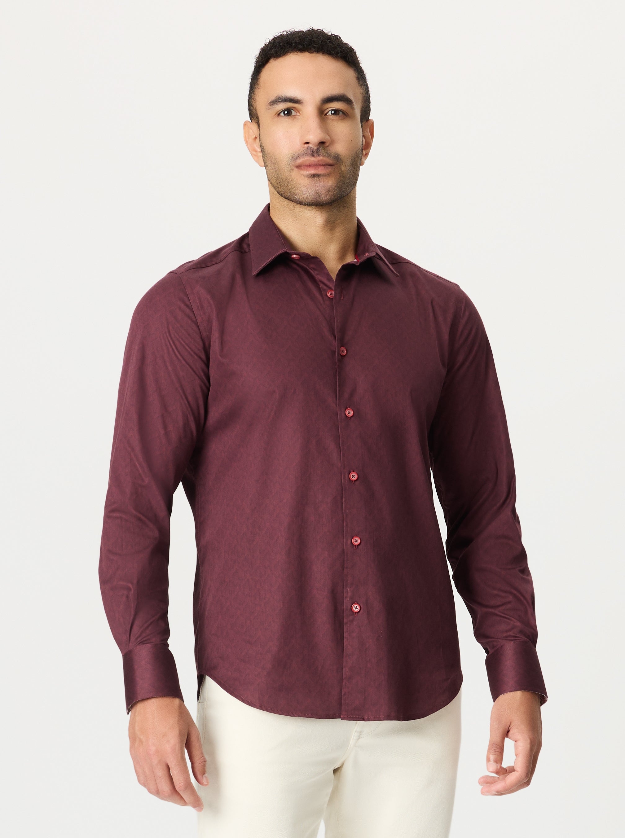 Man wearing a maroon shirt with a geometric pattern and red buttons on a white background