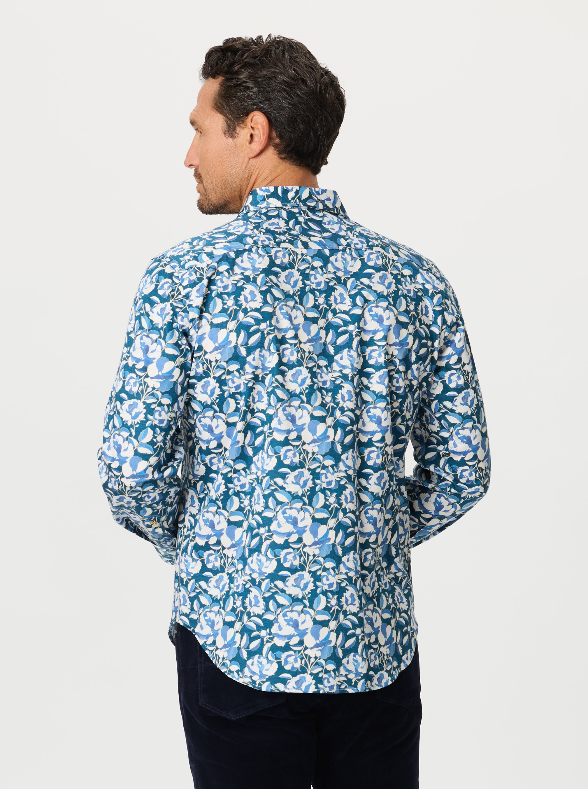 Man wearing a blue floral patterned shirt on a light gray background