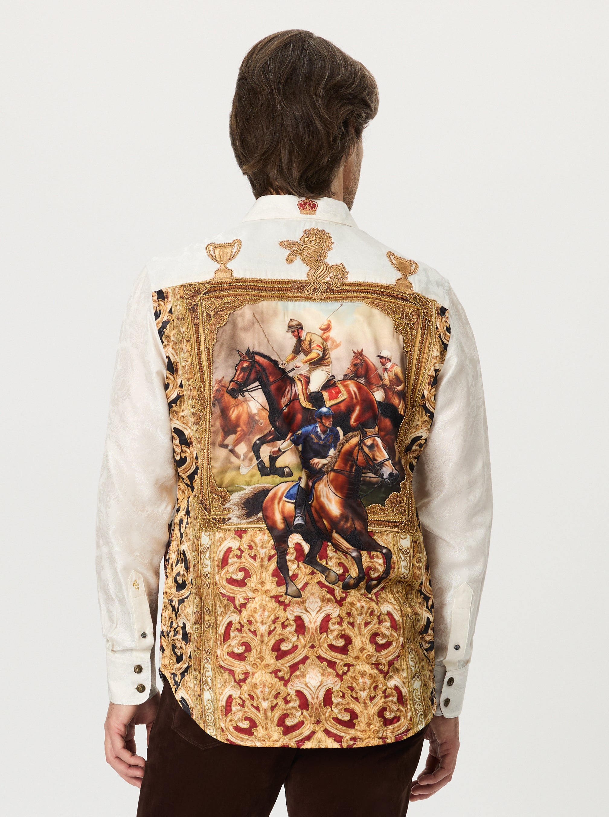 Person wearing a white shirt with an ornate embroidered back panel featuring horse and rider design.
