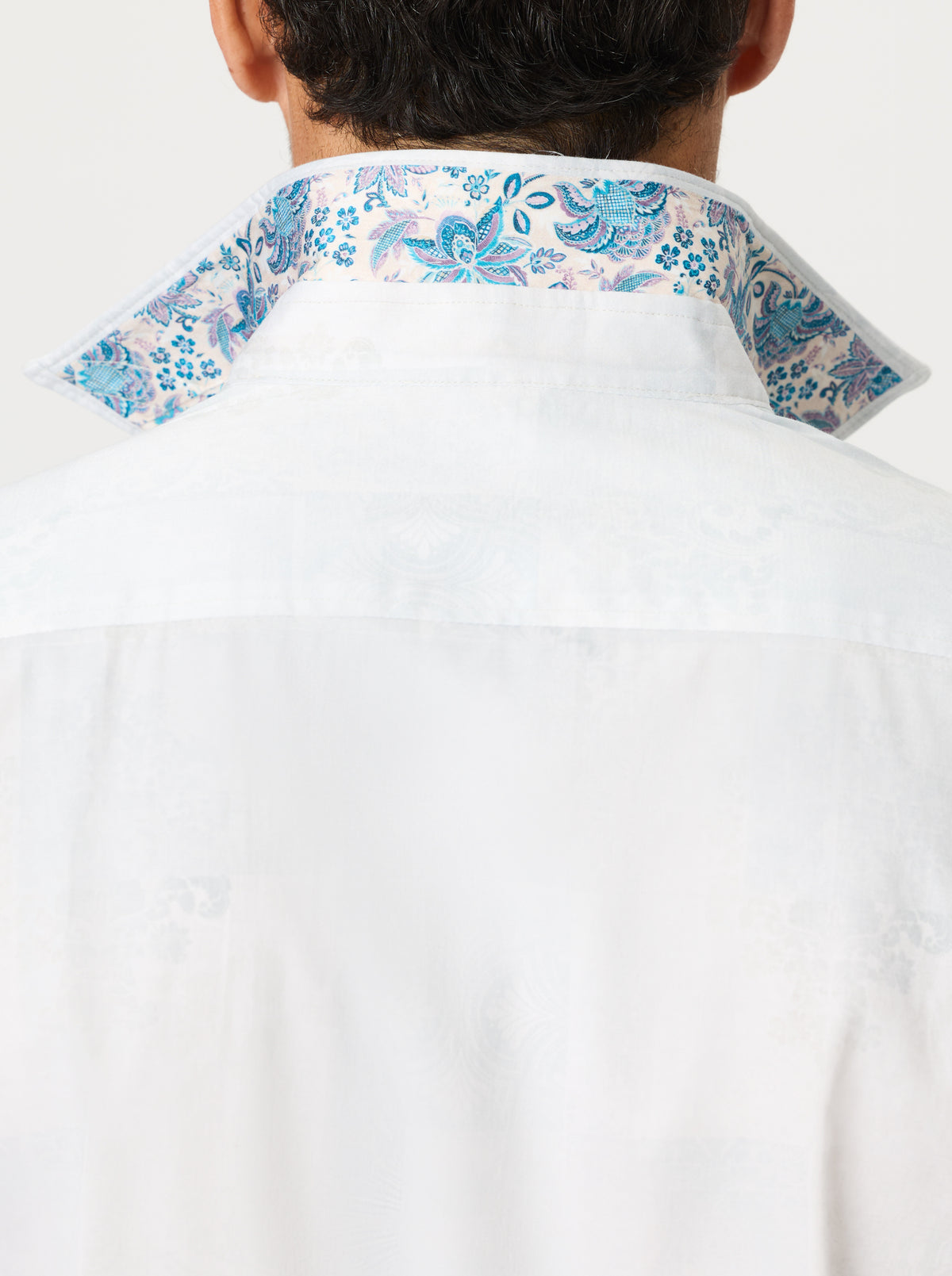 White shirt with blue floral patterns on collar and cuffs against a white background