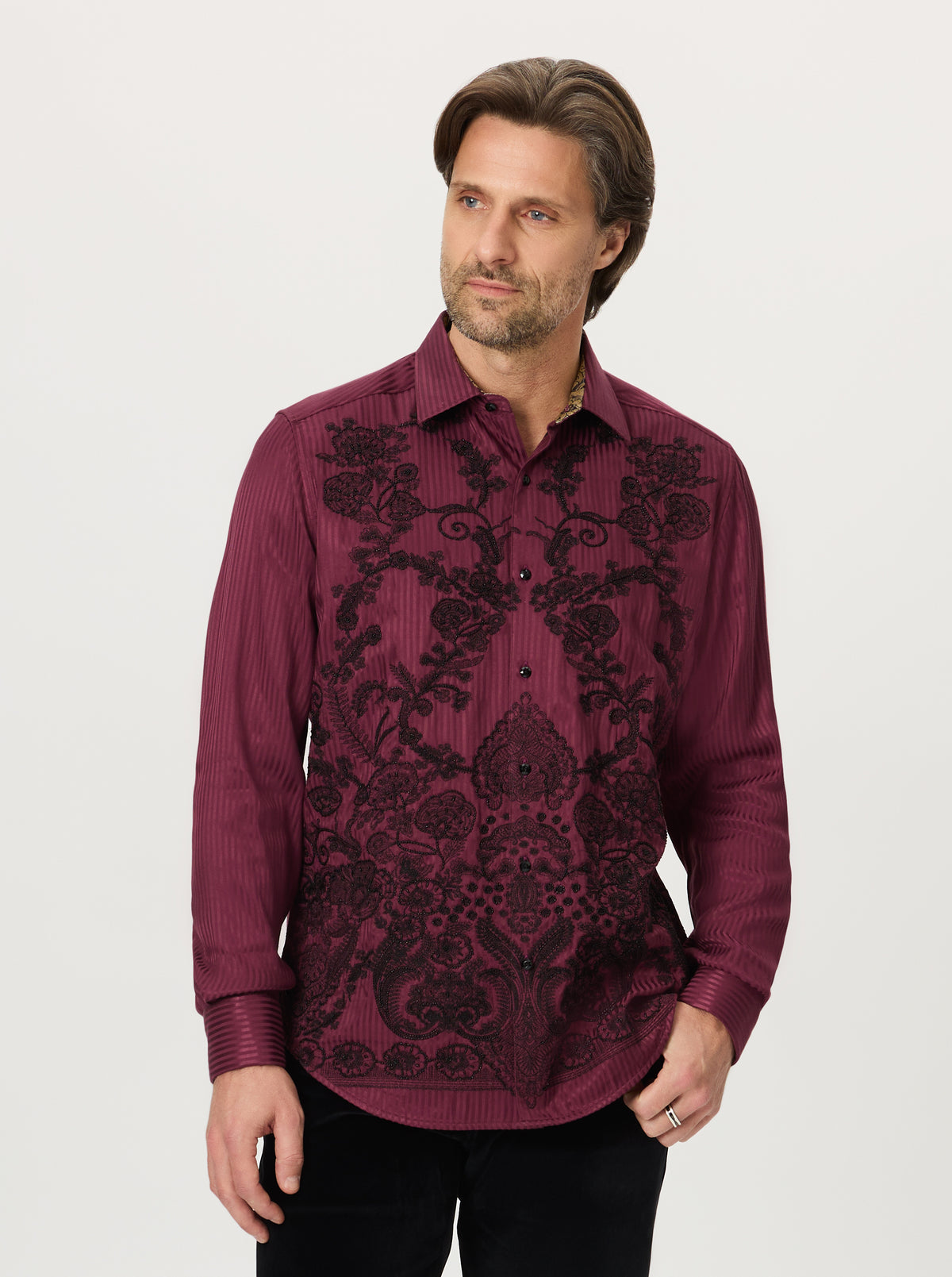 Man wearing a burgundy embroidered shirt on a white background