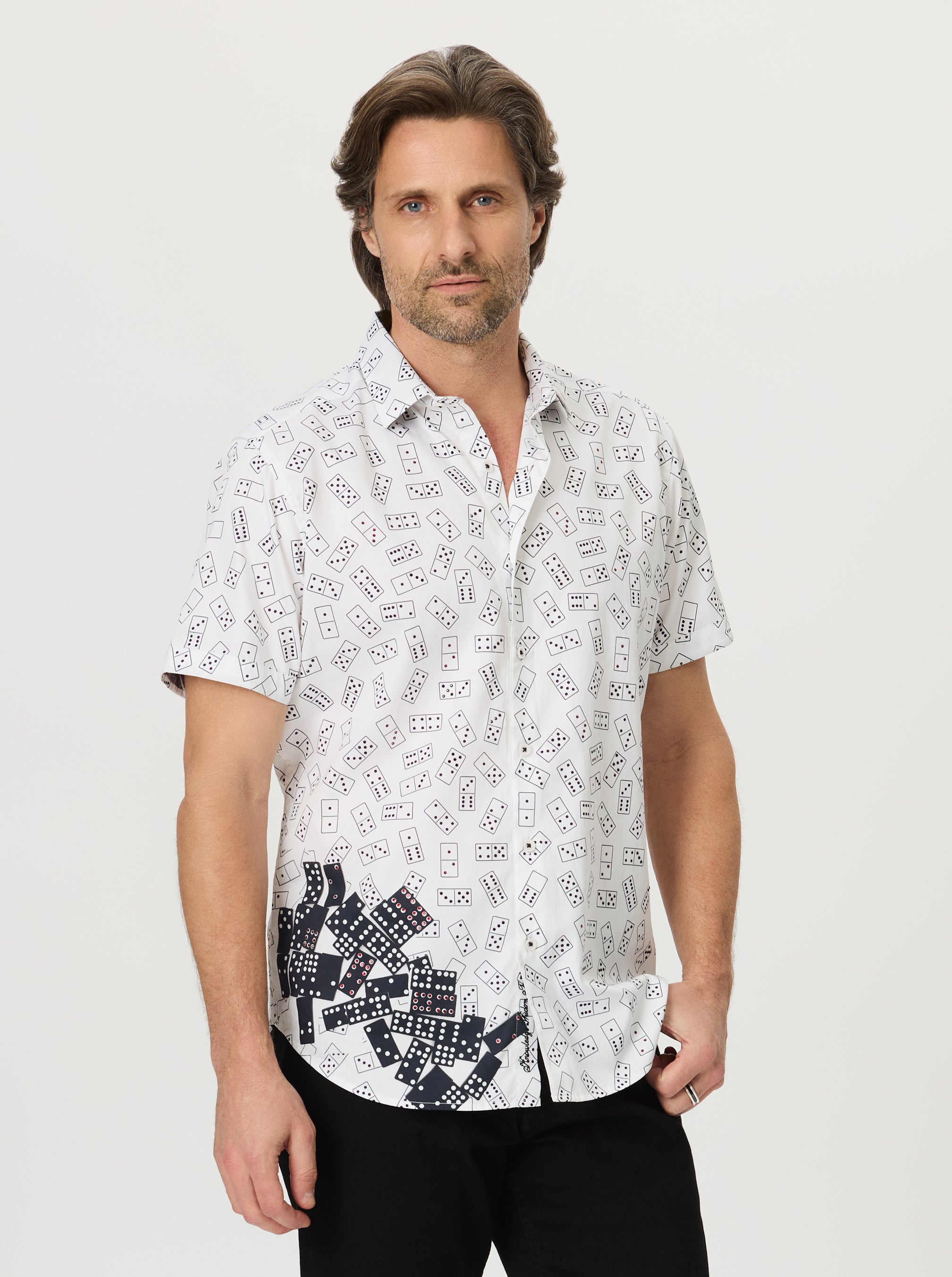 Man wearing a white shirt with black domino pattern on a light gray background