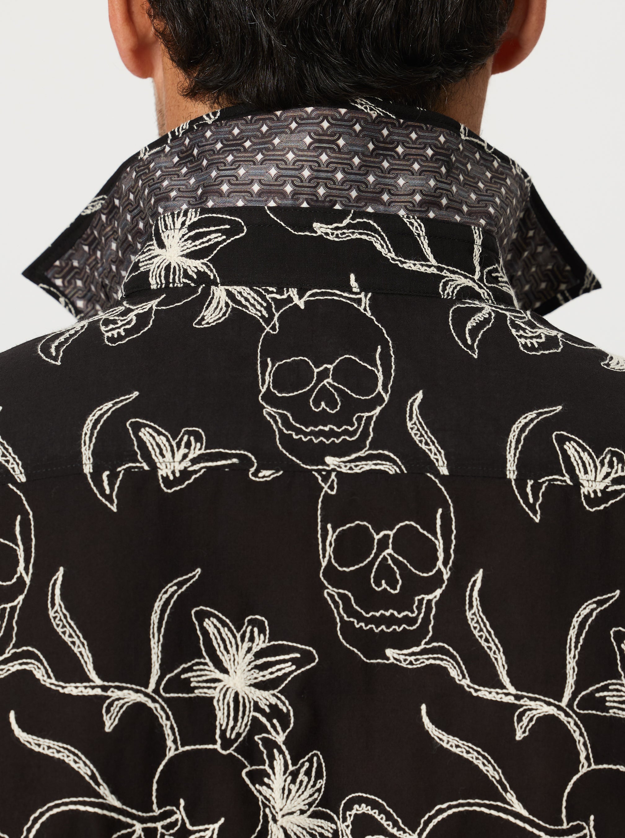Black shirt with white skull and floral pattern worn by a person