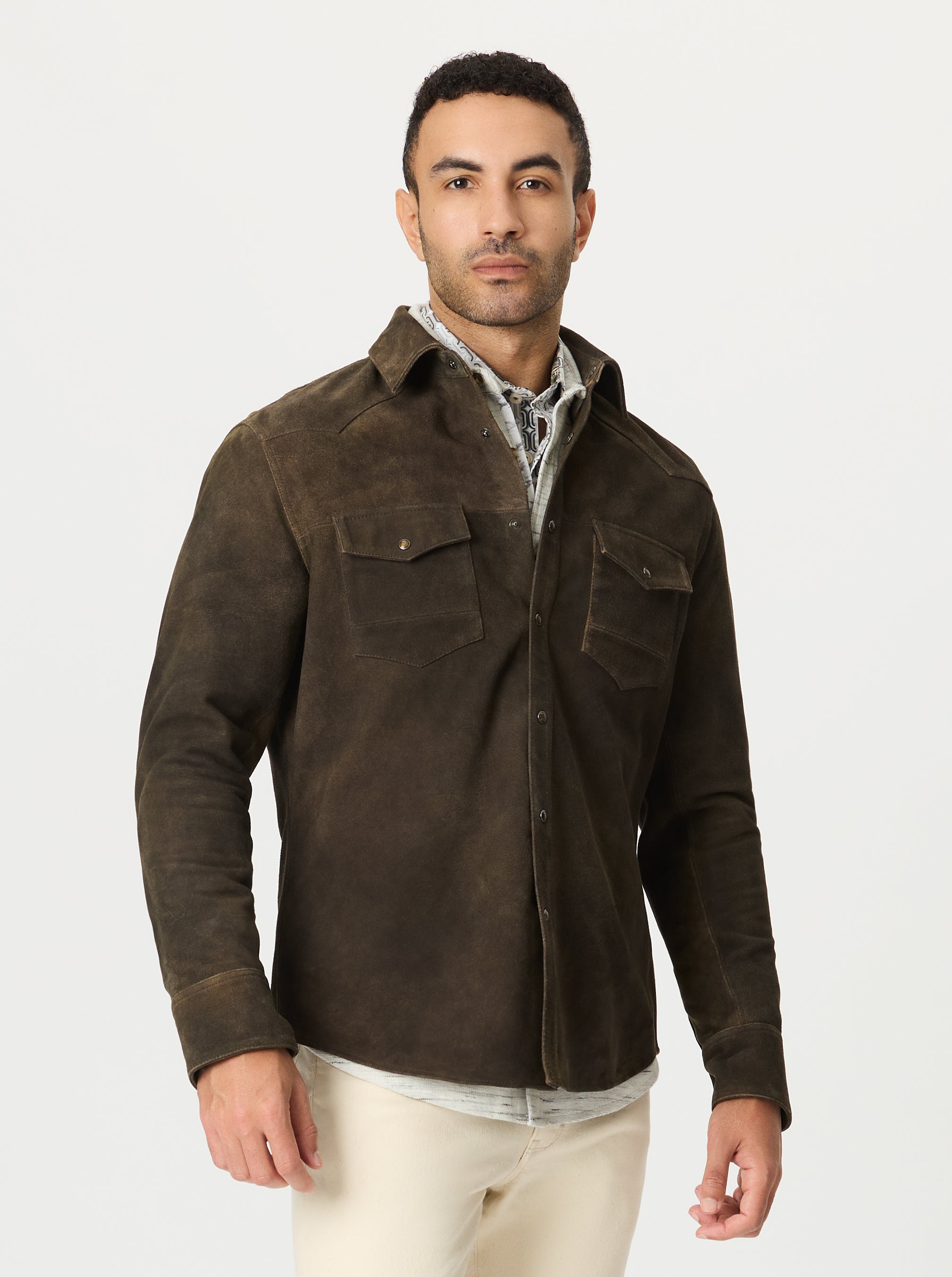 Man wearing a brown suede jacket over a shirt on a grey background