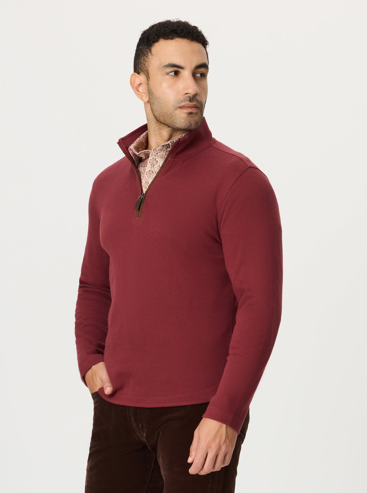 Man wearing a burgundy pullover with a patterned collar on a white background