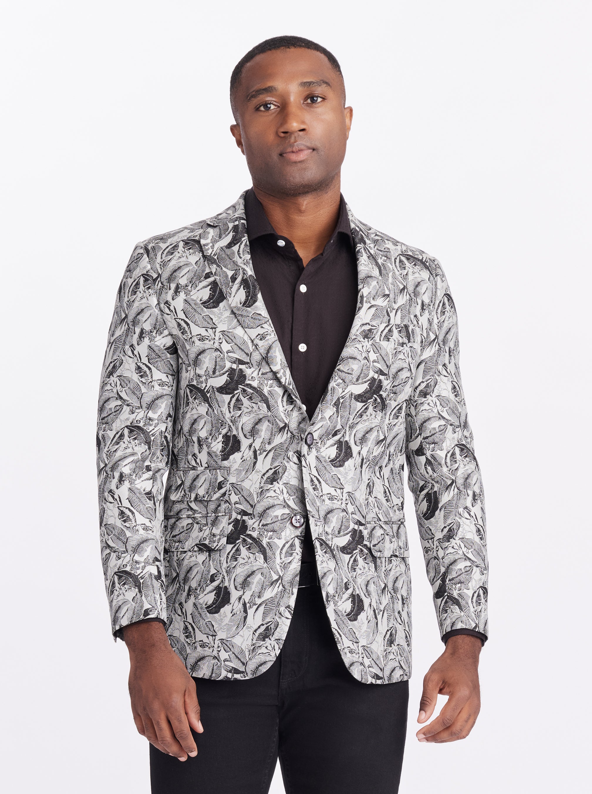 Man wearing a patterned blazer over a black shirt on a white background