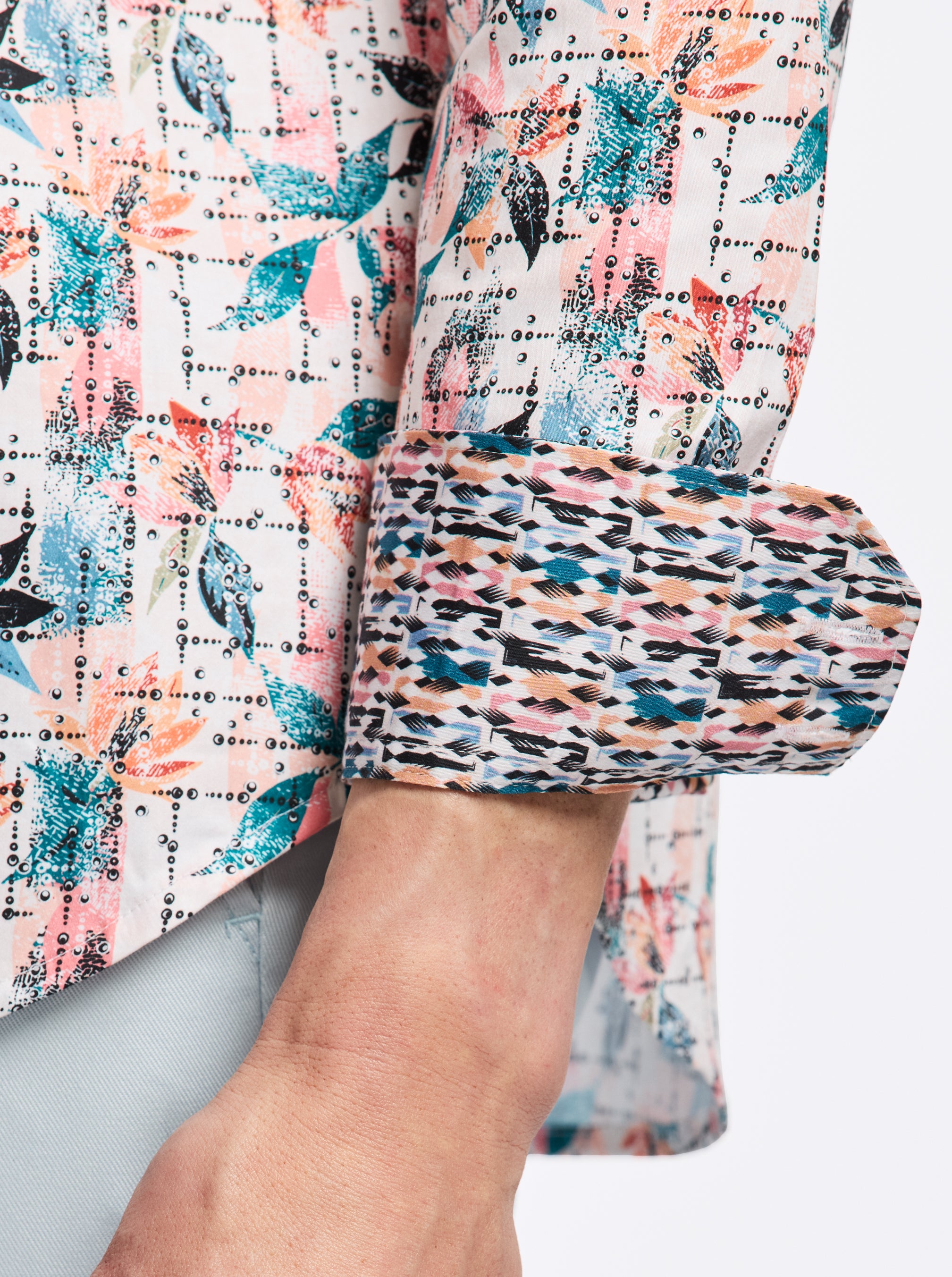 Close-up of a colorful patterned shirt with rolled-up sleeves on a neutral background