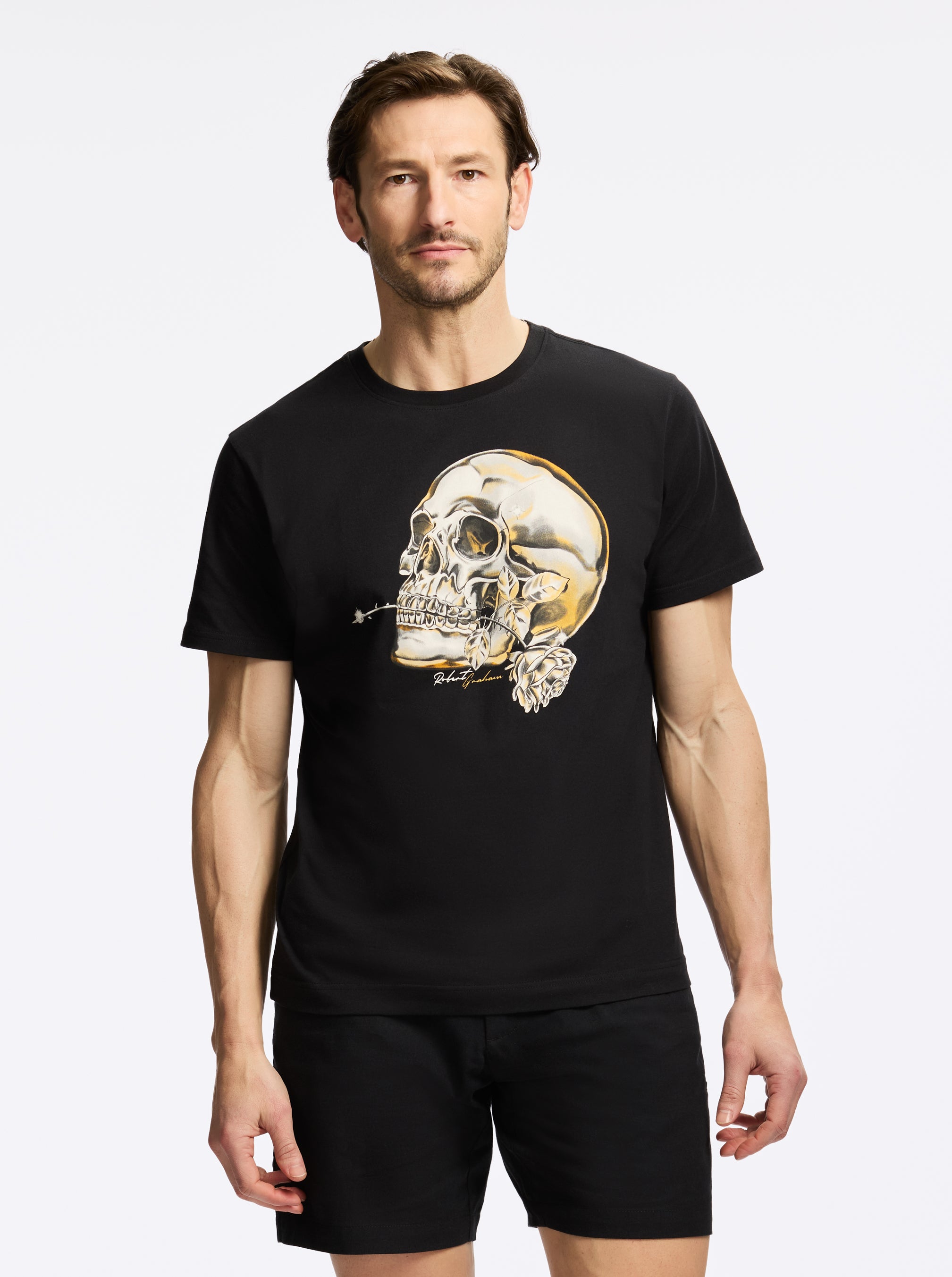 Man wearing a black t-shirt with a skull design on a plain background