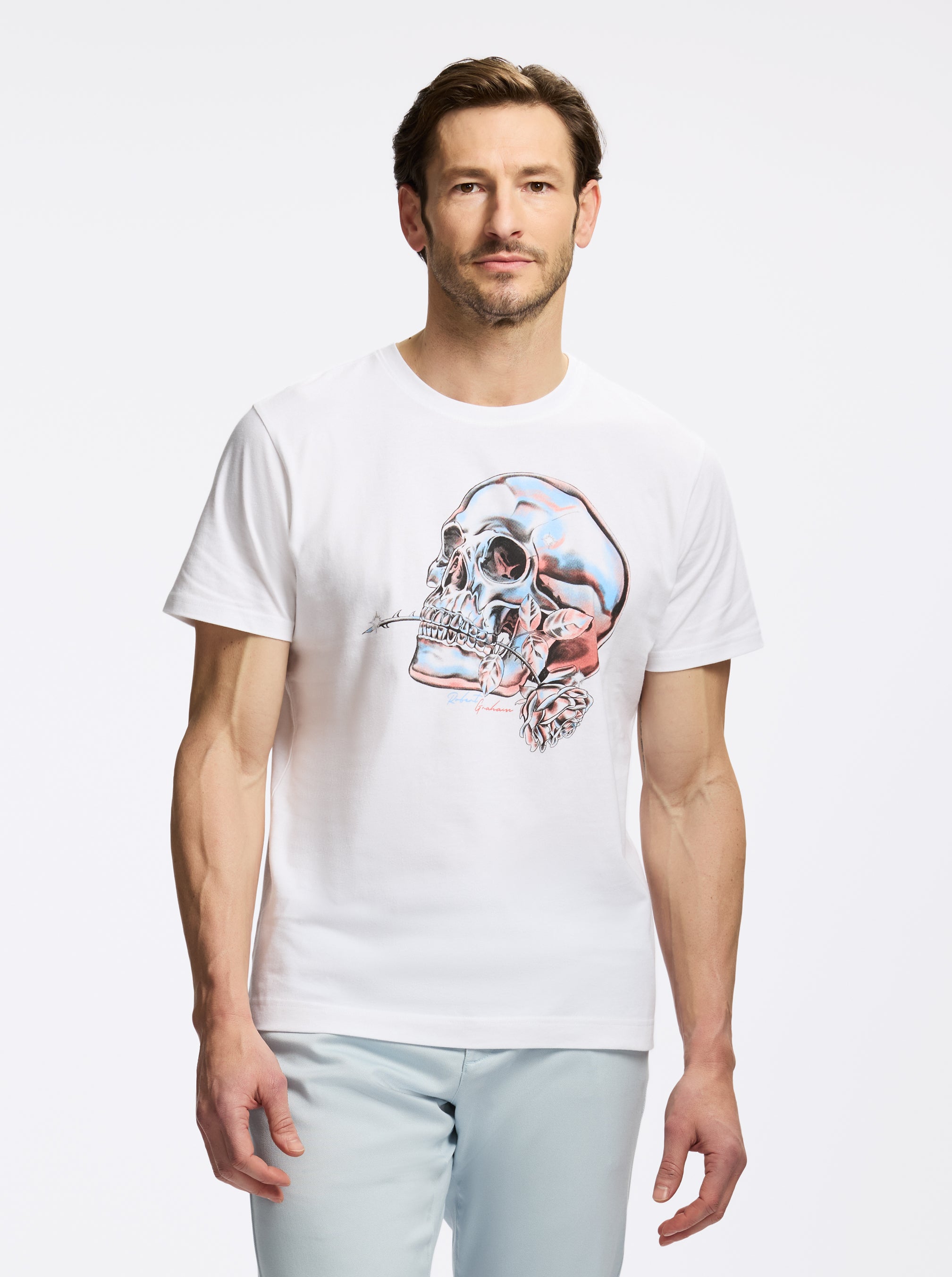 Man wearing a white t-shirt with a colorful skull design on a plain background