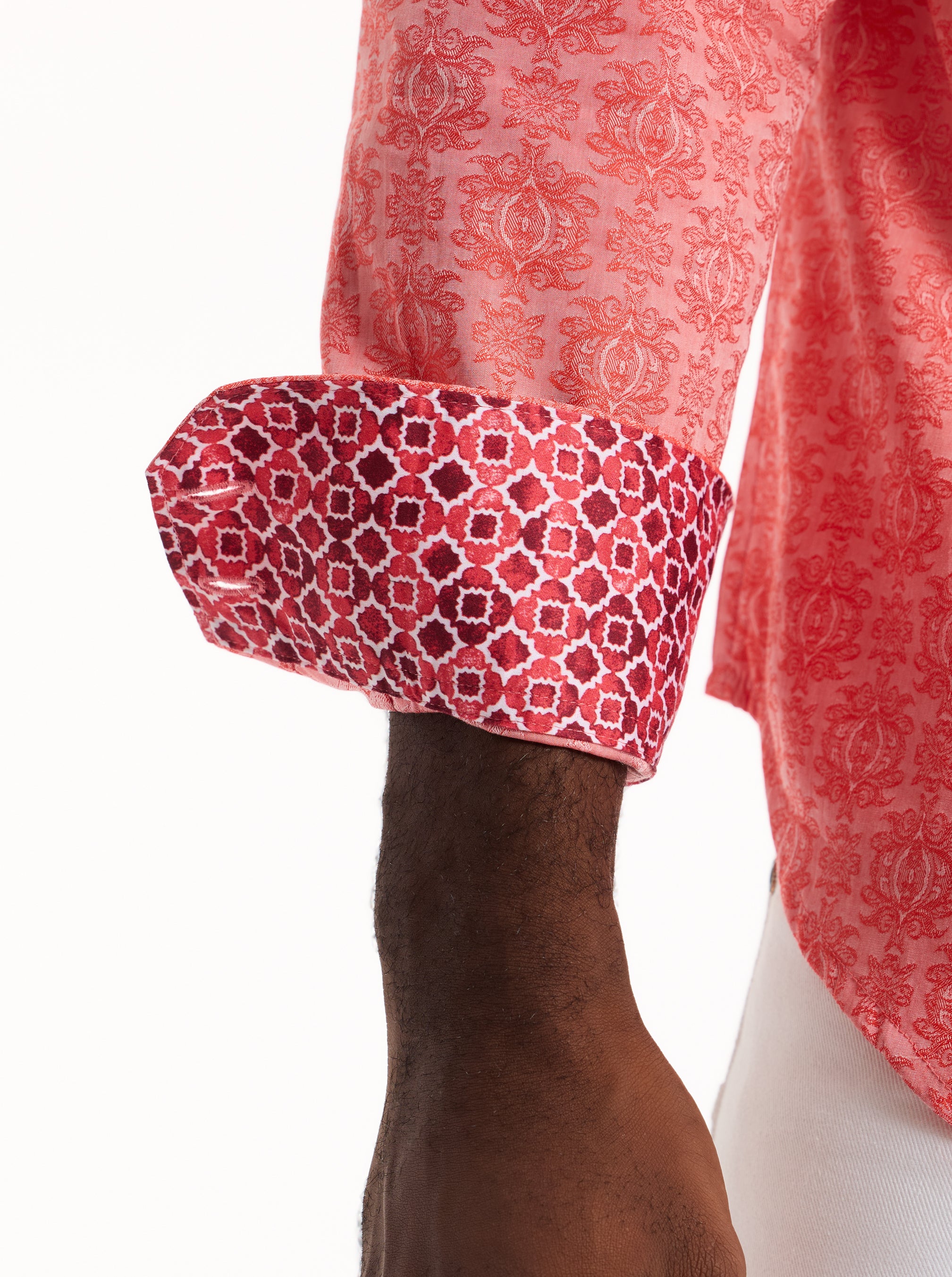 Close-up of a red patterned shirt with cuffed sleeves on a white background