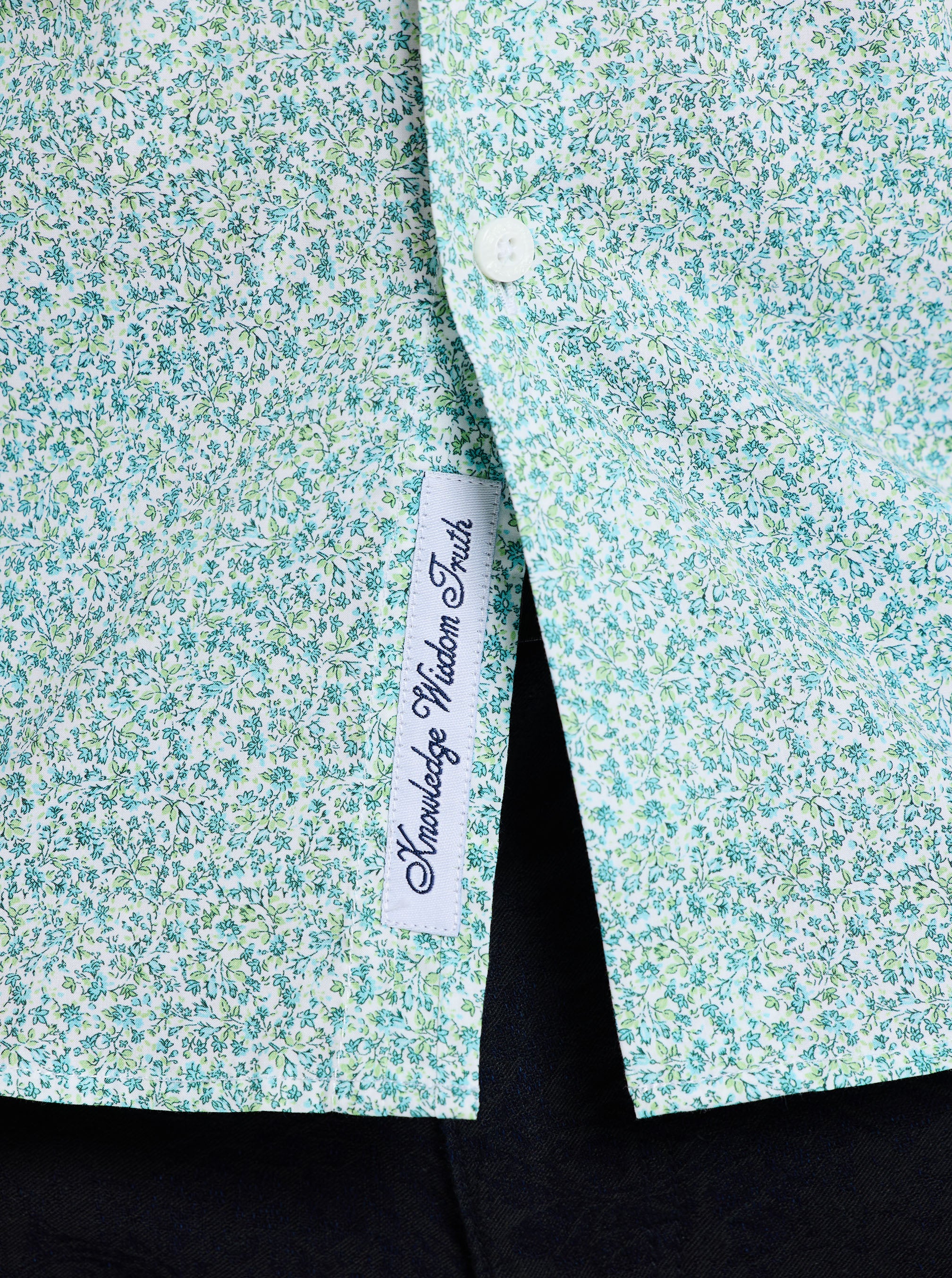 Close-up of a floral-patterned shirt with a label on a black background