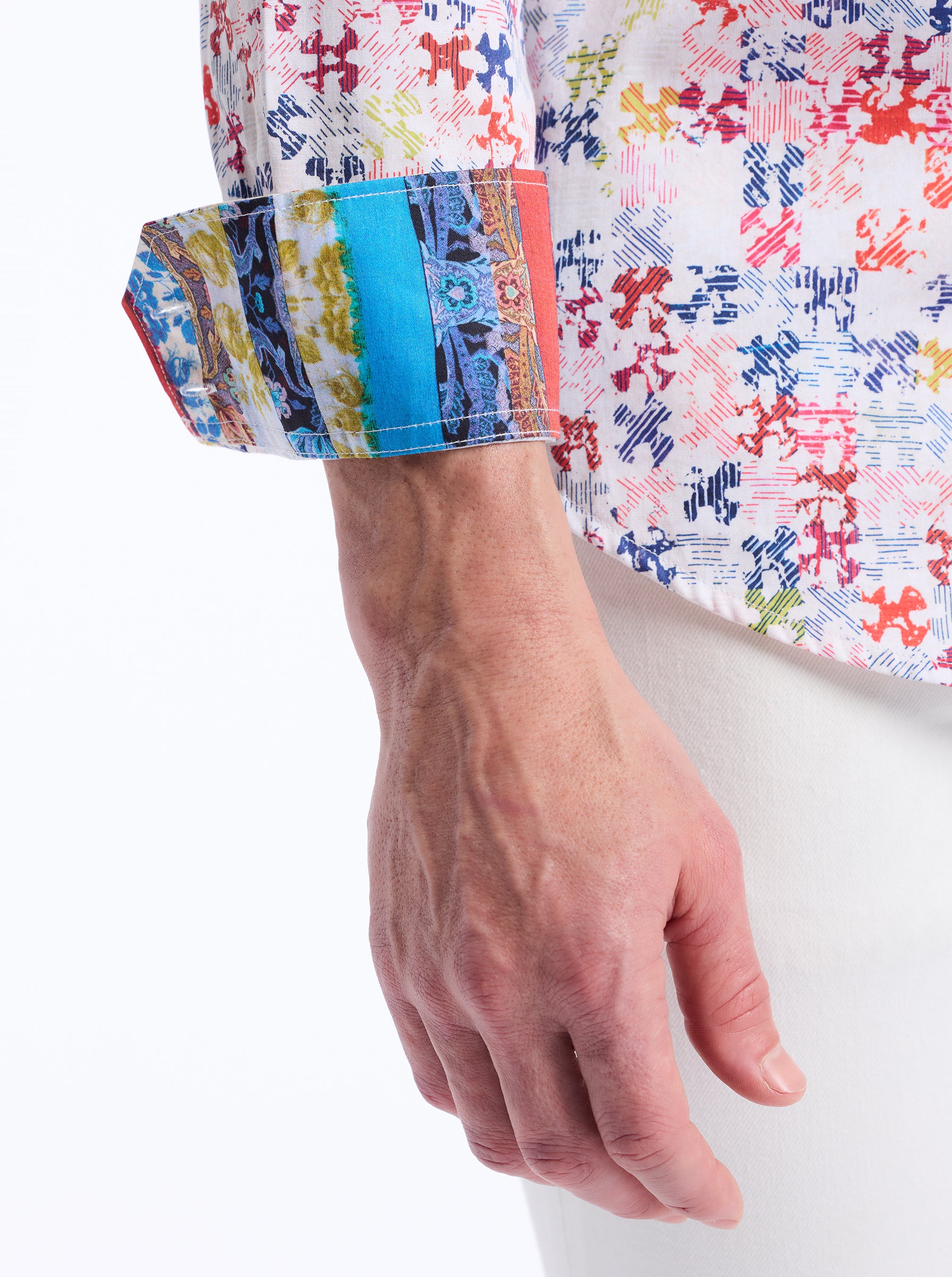 Close-up of a colorful puzzle patterned shirt with a contrast patterned sleeve cuff on a white background
