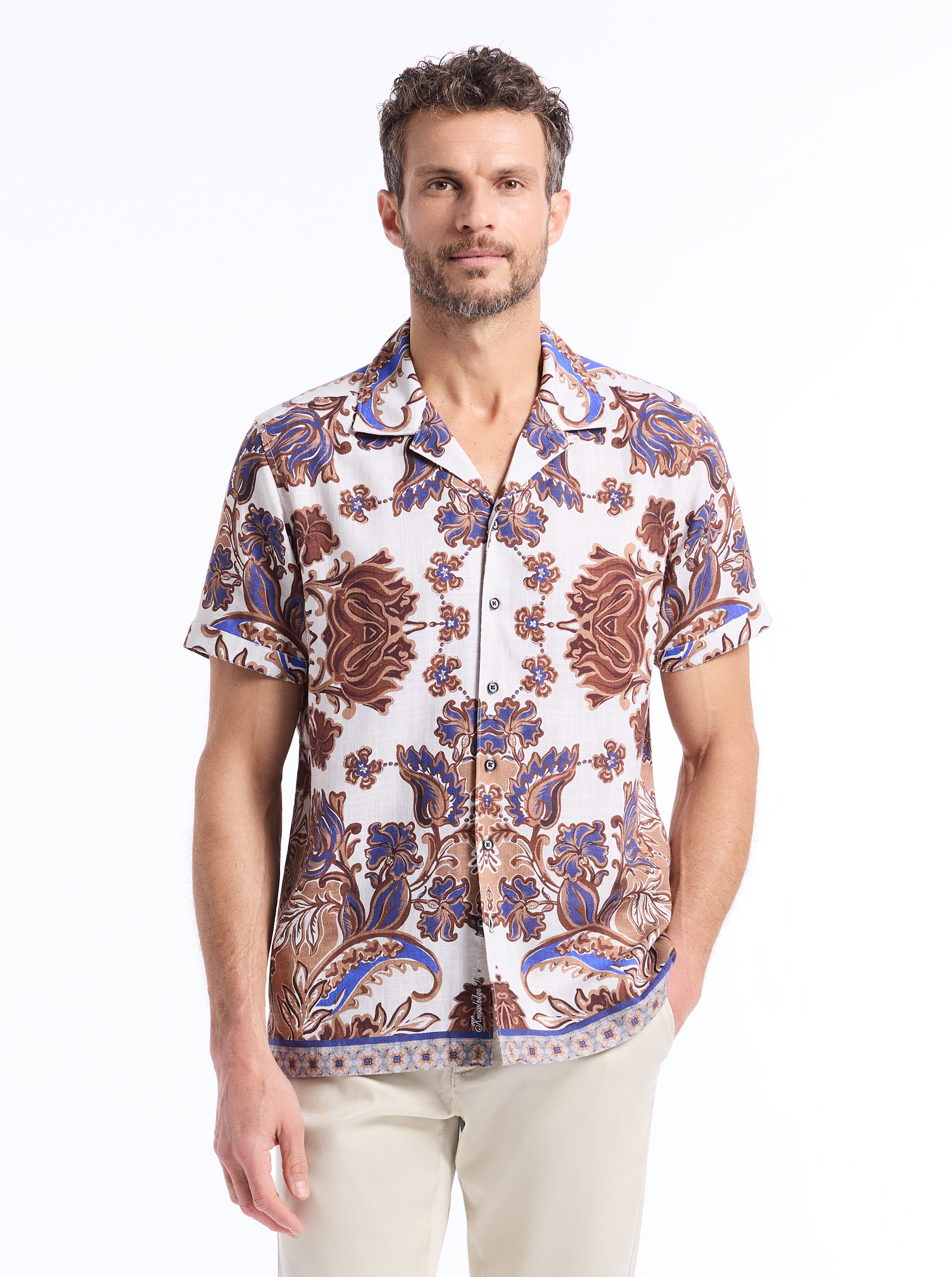 Man wearing a ornate and floral patterned shirt on a white background