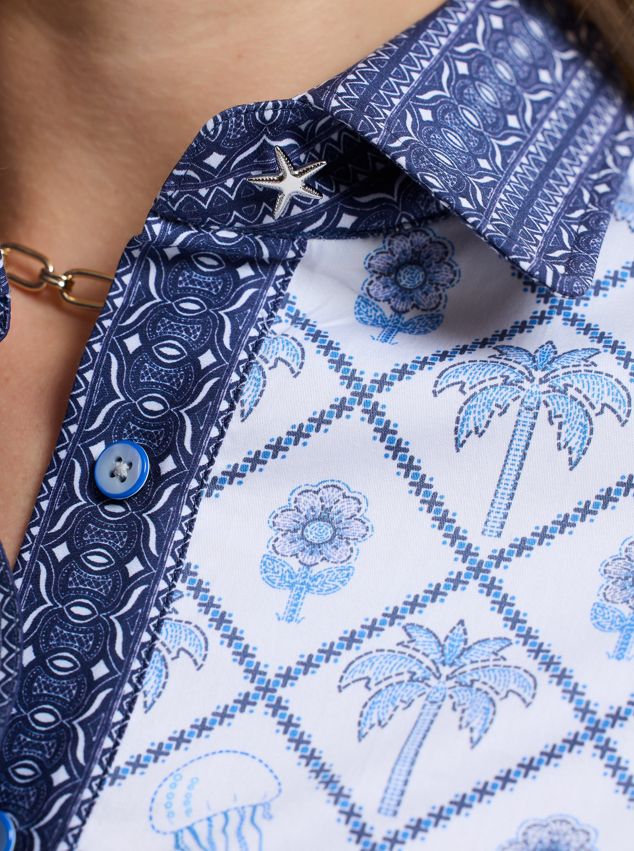 Close-up of a patterned shirt with blue and white palm trees and flowers design
