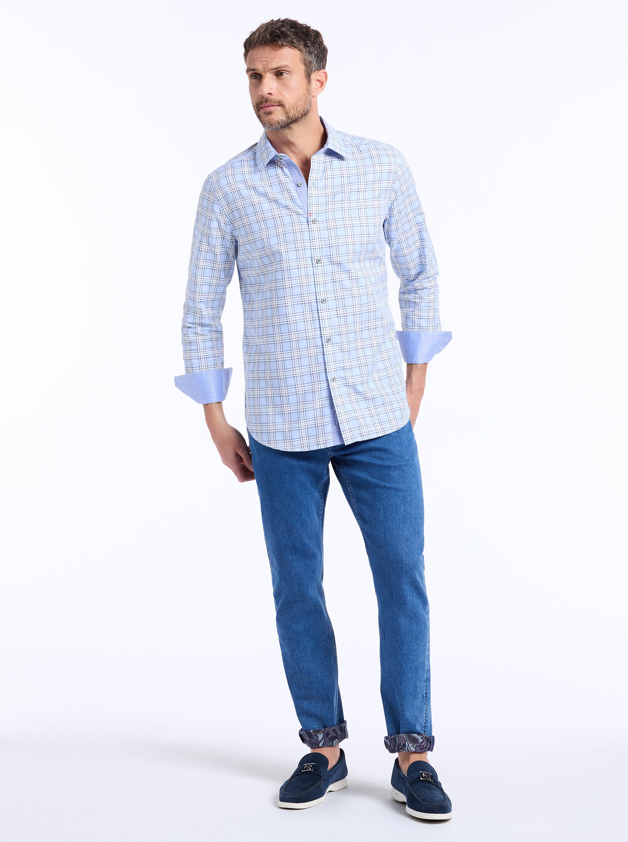 Man wearing a light blue checkered shirt and blue jeans on a white background
