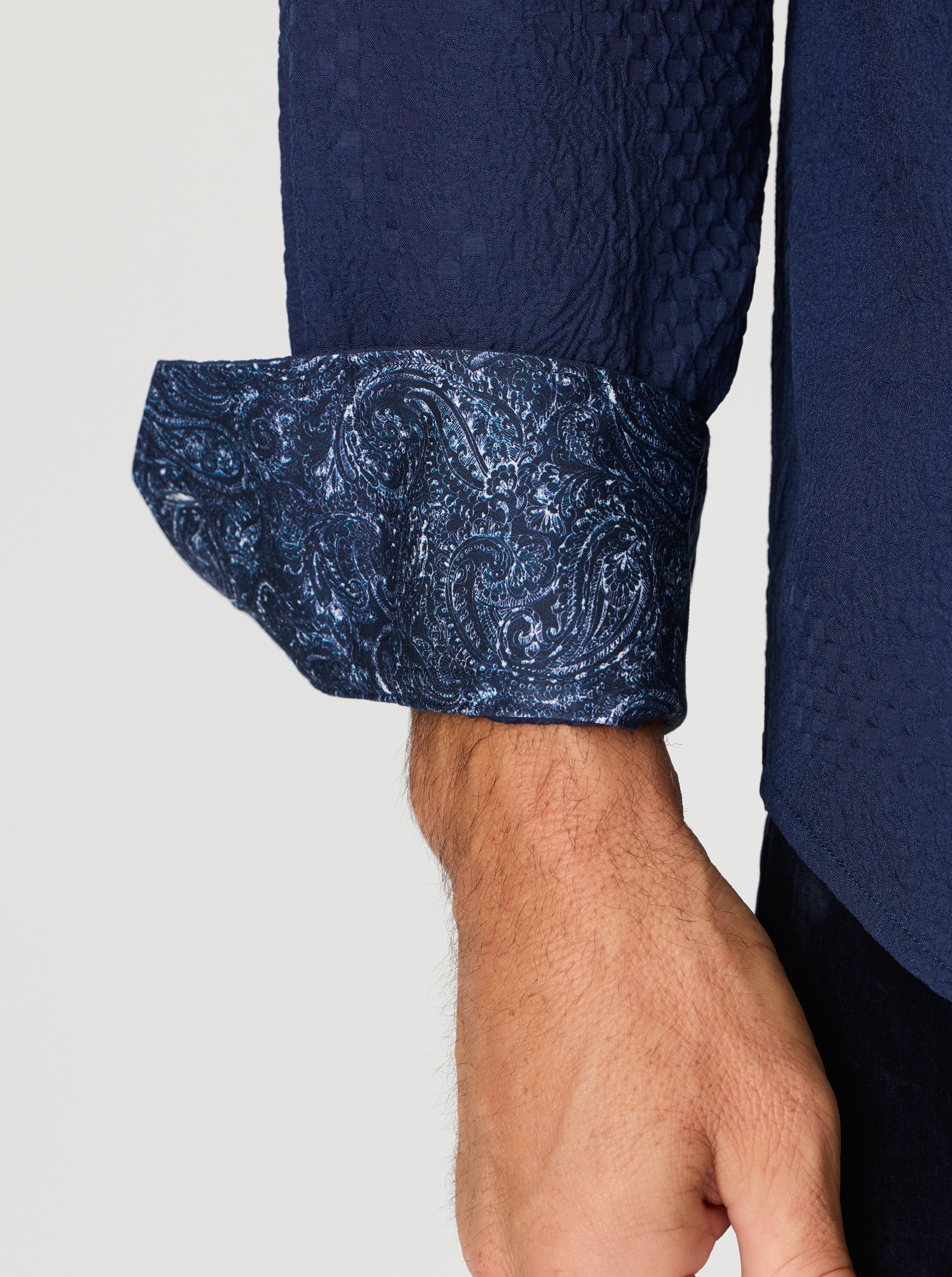 Close-up of a navy blue shirt with texture cuff on a light gray background