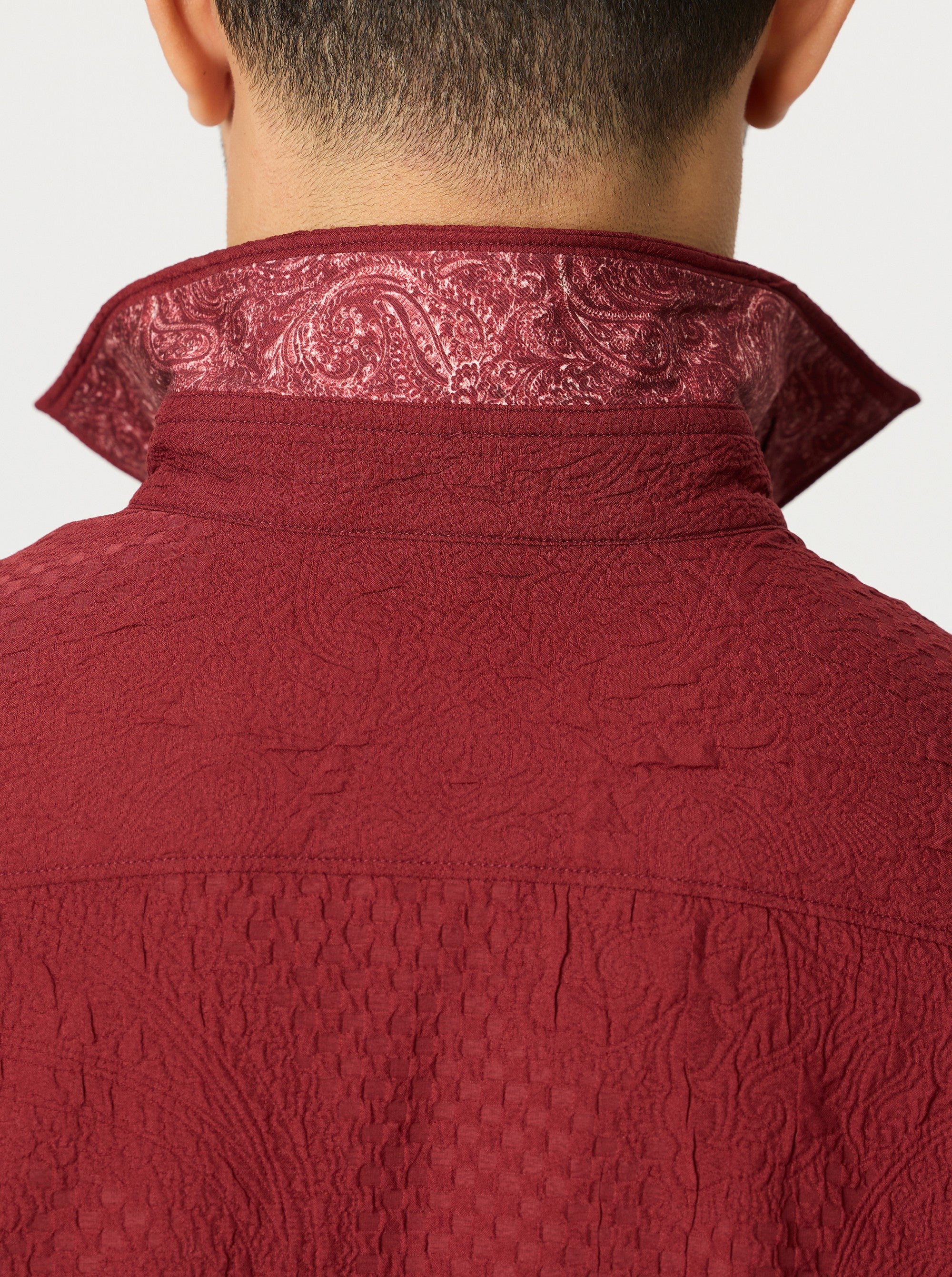 Close-up of a red textured garment with intricate patterns on a white background