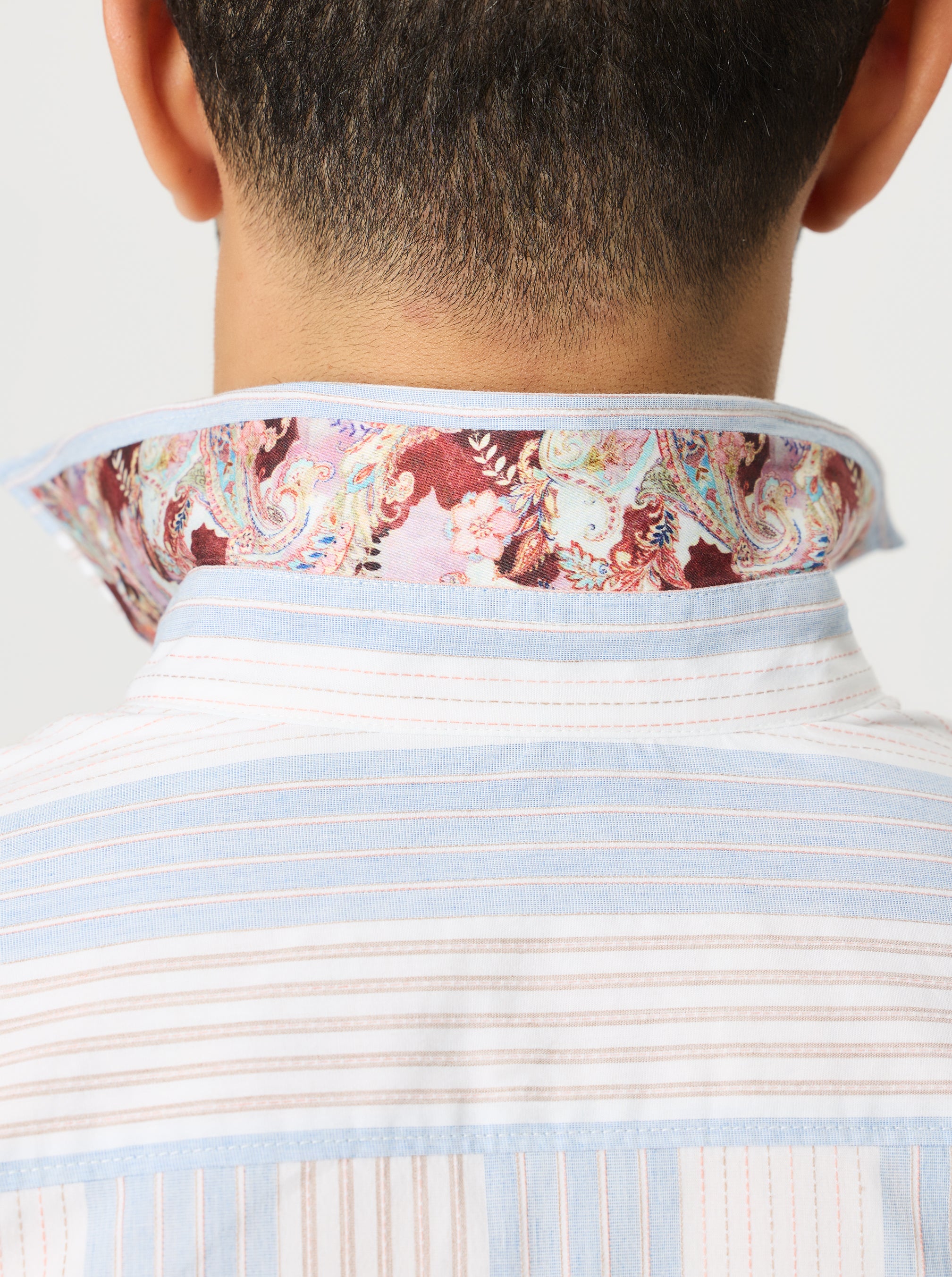Close-up of a person wearing a striped shirt with a floral patterned collar.