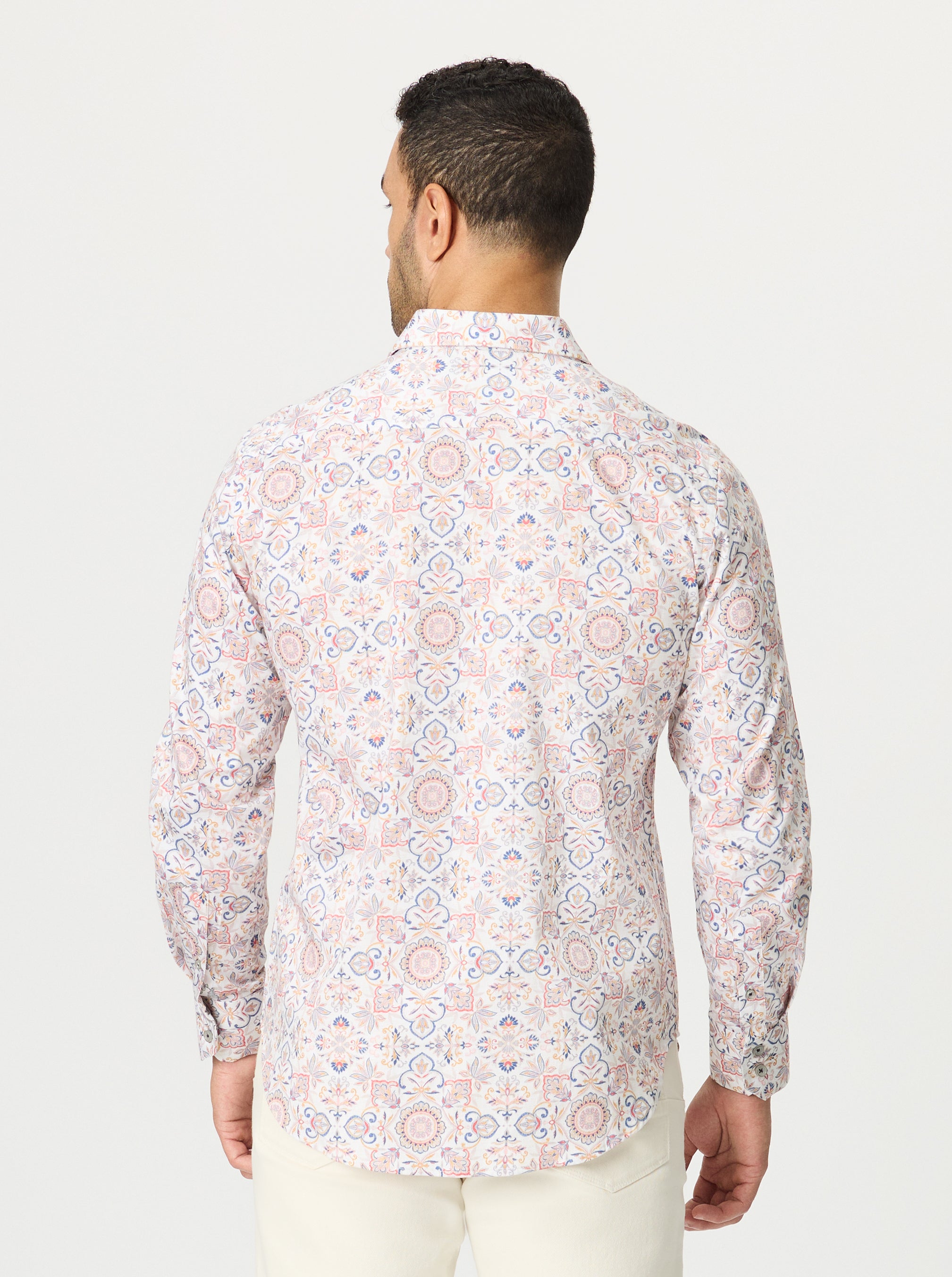 Man wearing a geometric floral medallion patterned shirt on a white background