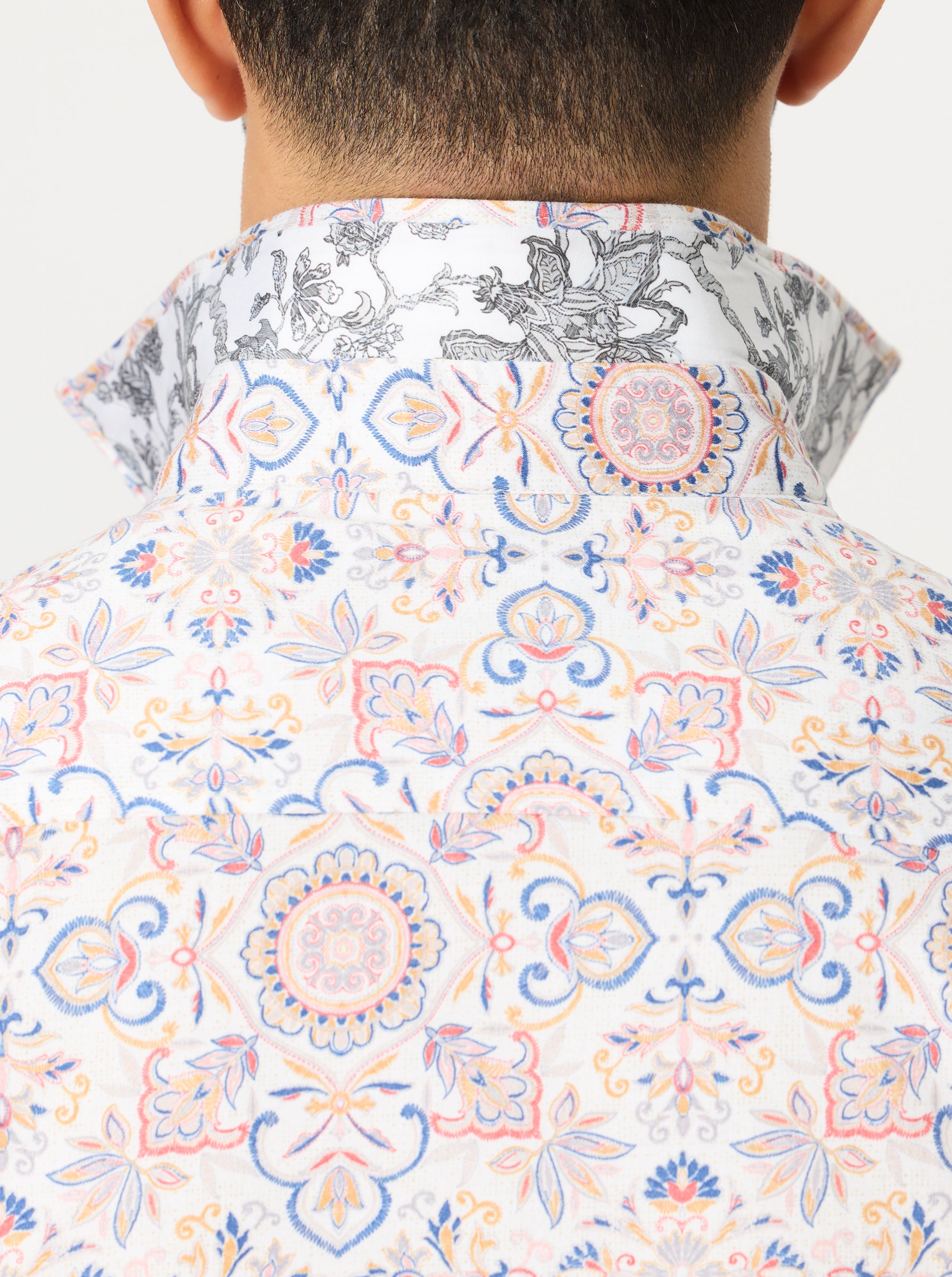 Close-up of a colorful patterned shirt with intricate designs on a white background