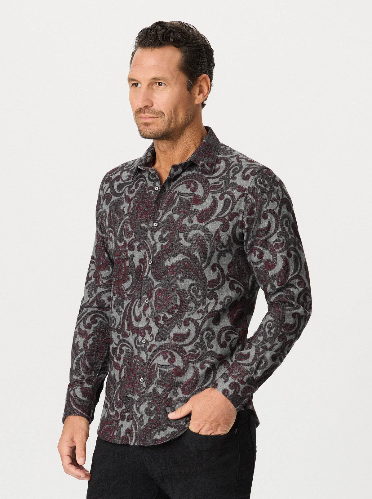 Man wearing a paisley patterned shirt on a plain background
