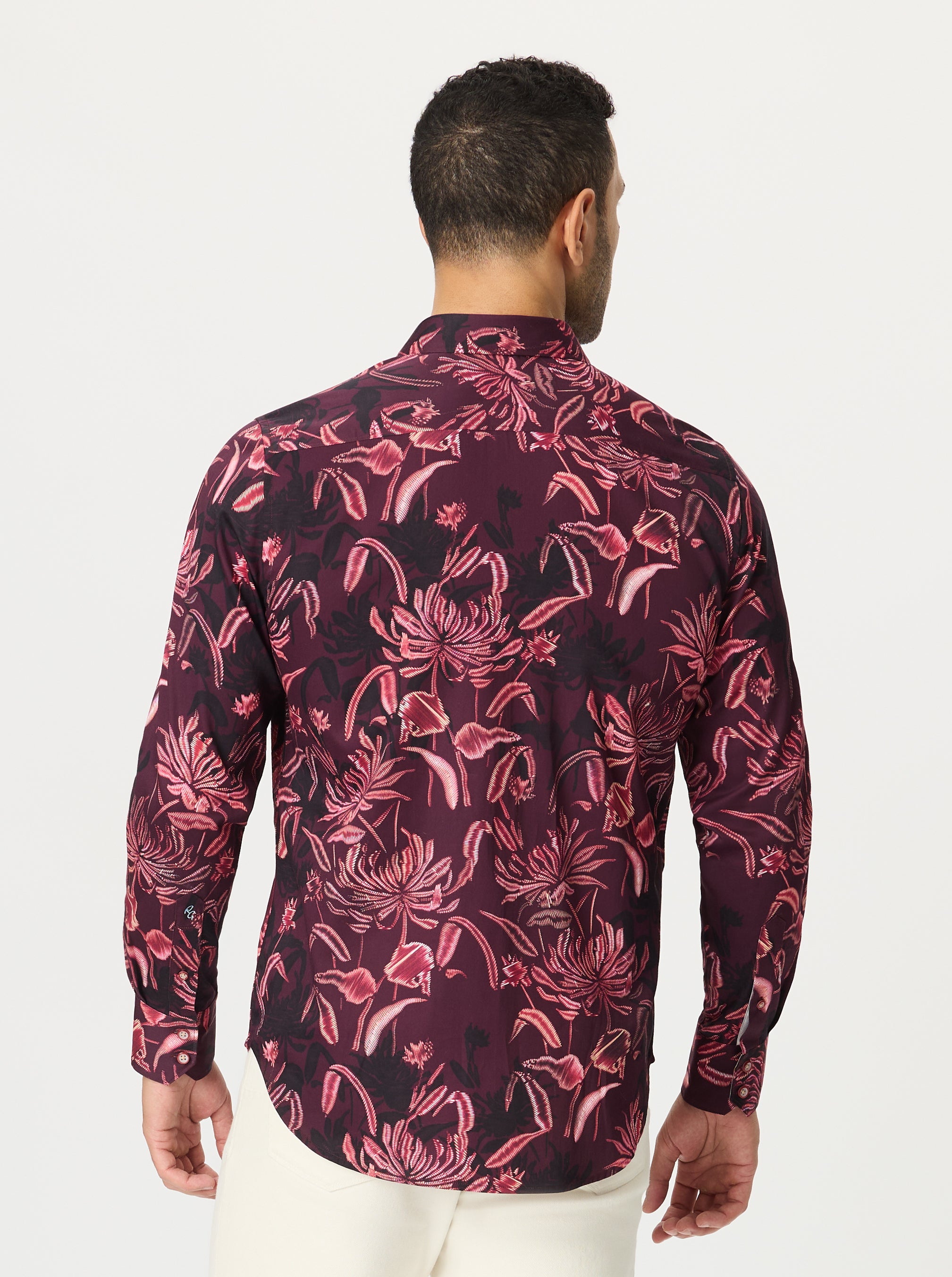 Man wearing a patterned shirt with pink floral design on a white background