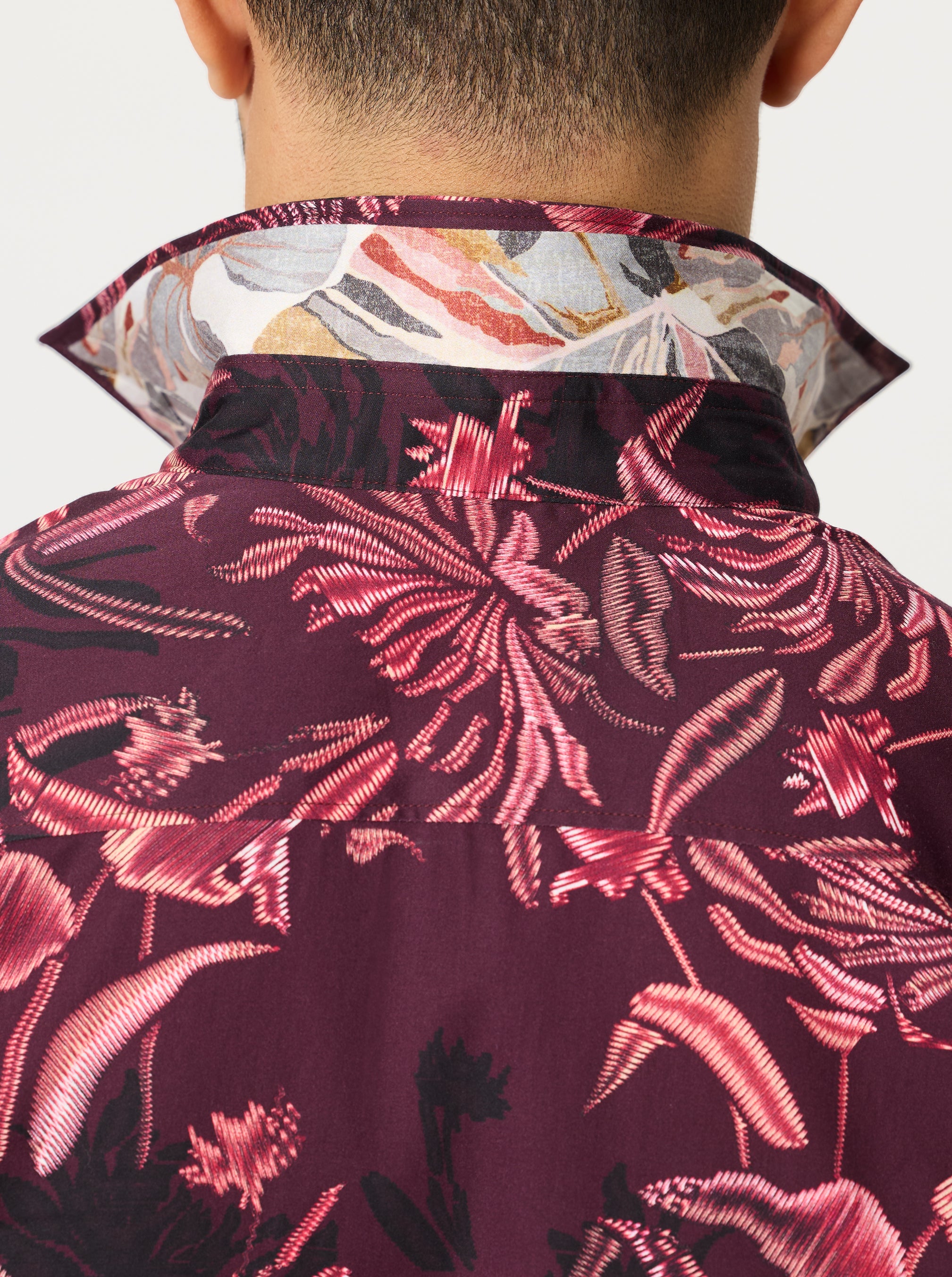 Close-up of a person wearing a floral patterned shirt with a dark background
