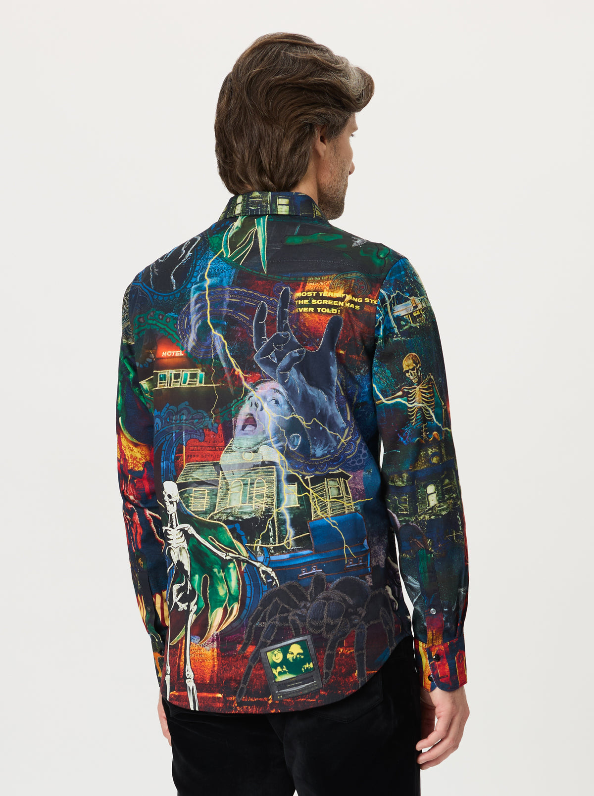Person wearing a colorful, patterned shirt with abstract Halloween designs on a plain background