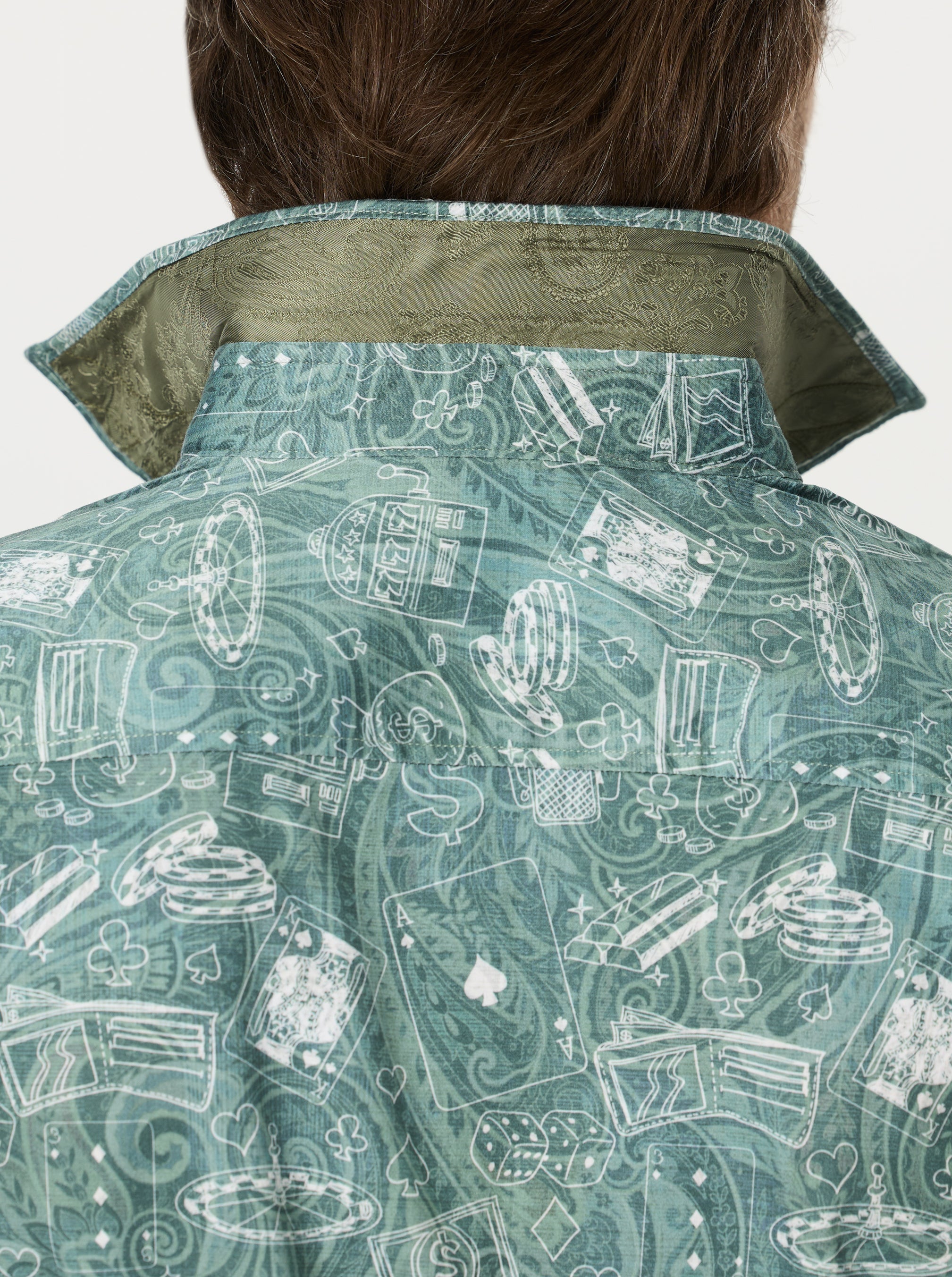 Close-up of a casino patterned shirt with a green collar on a plain background