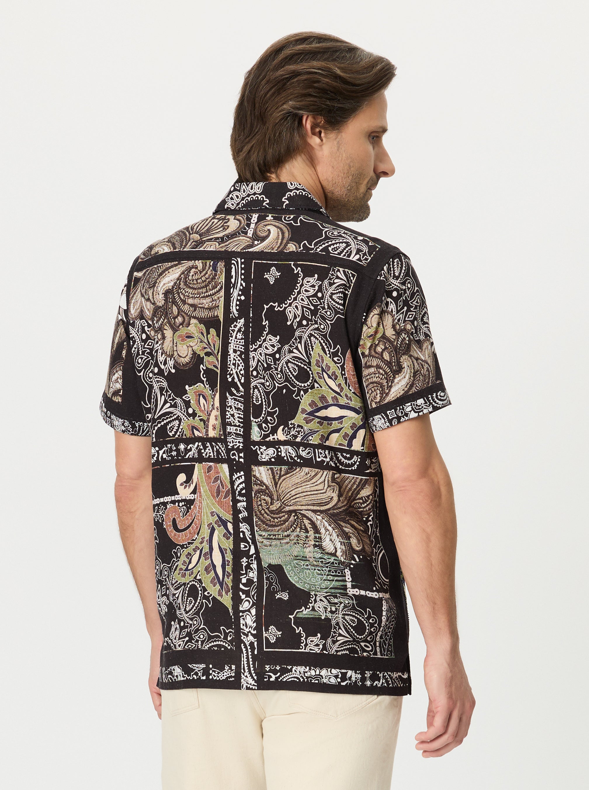 Man wearing a scroll patterned shirt with a white background