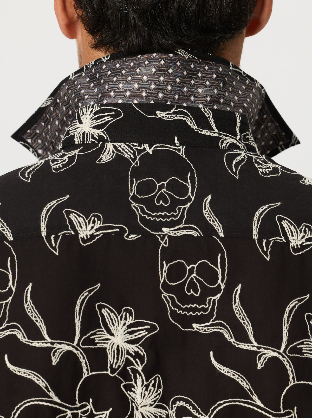 Black shirt with white skull and floral pattern worn by a person