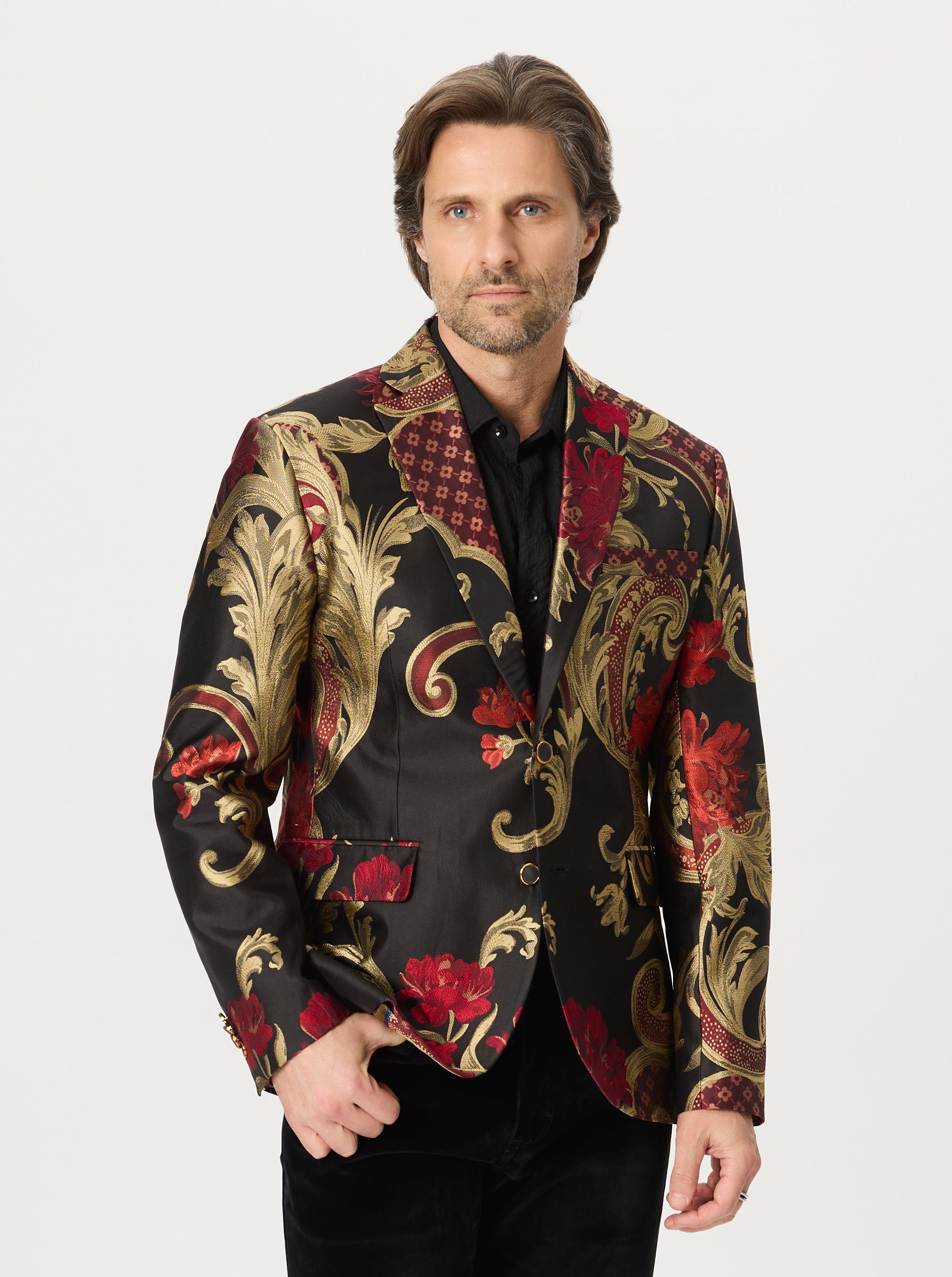 Man wearing a patterned blazer with red and gold designs on a white background