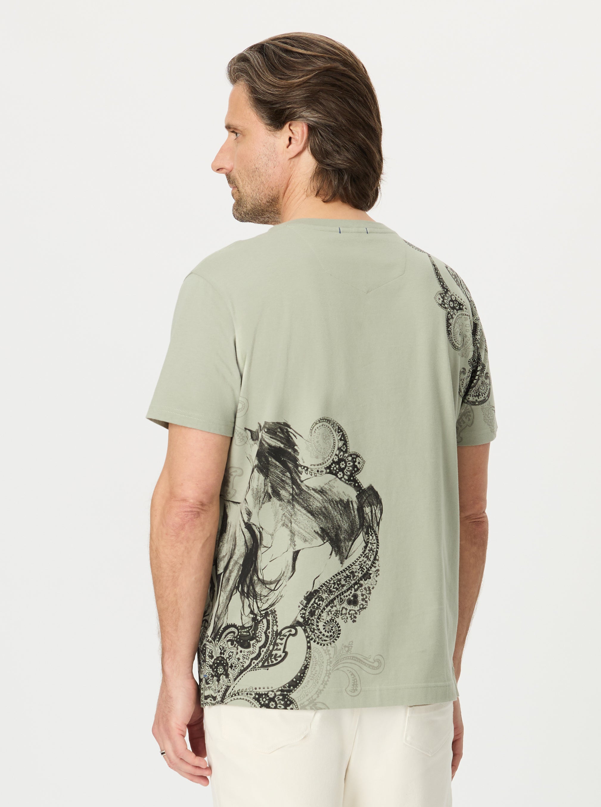 Man wearing a green t-shirt with a black graphic design on the back against a white background