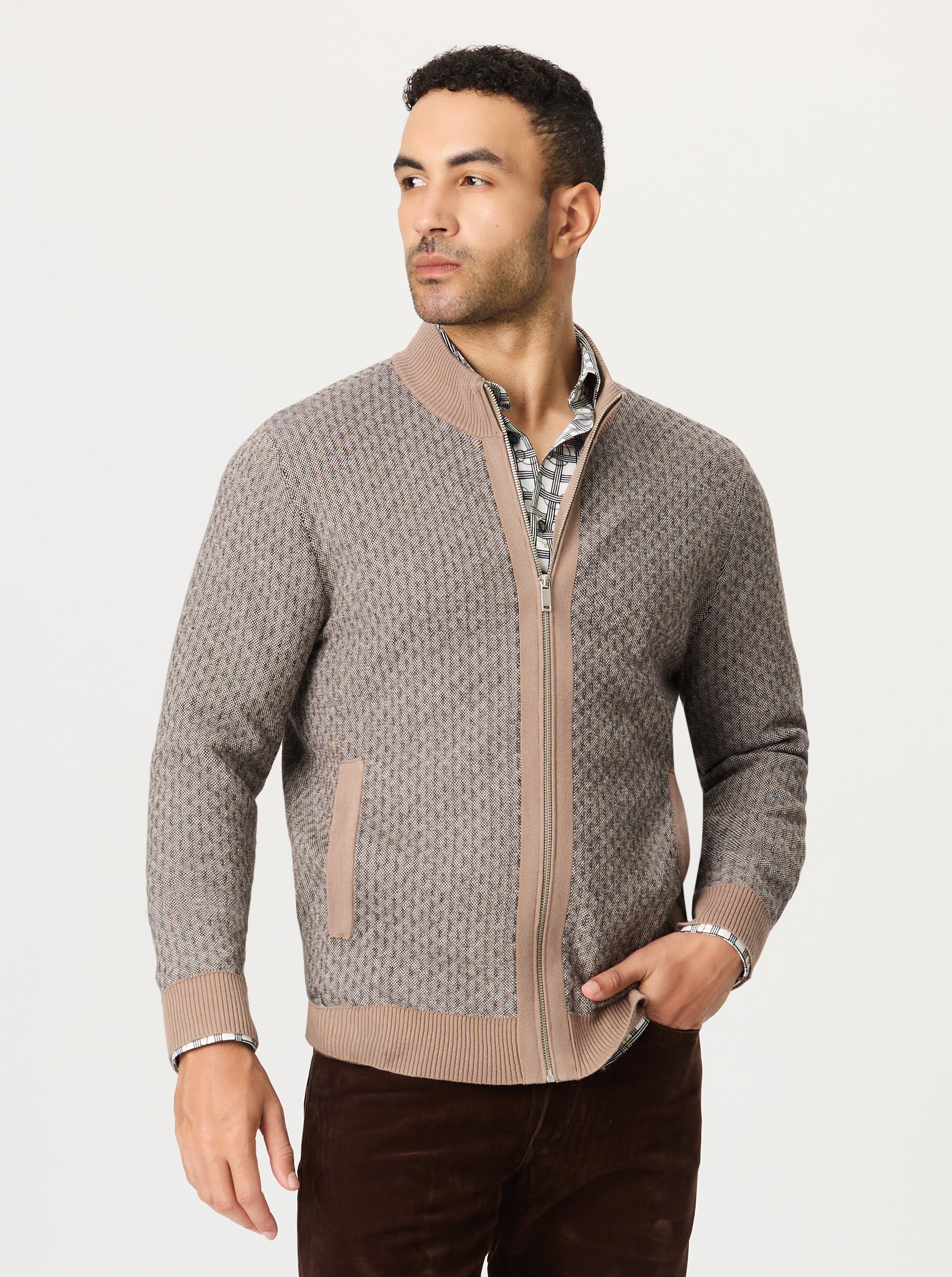 Man wearing a patterned zip-up sweater on a light gray background