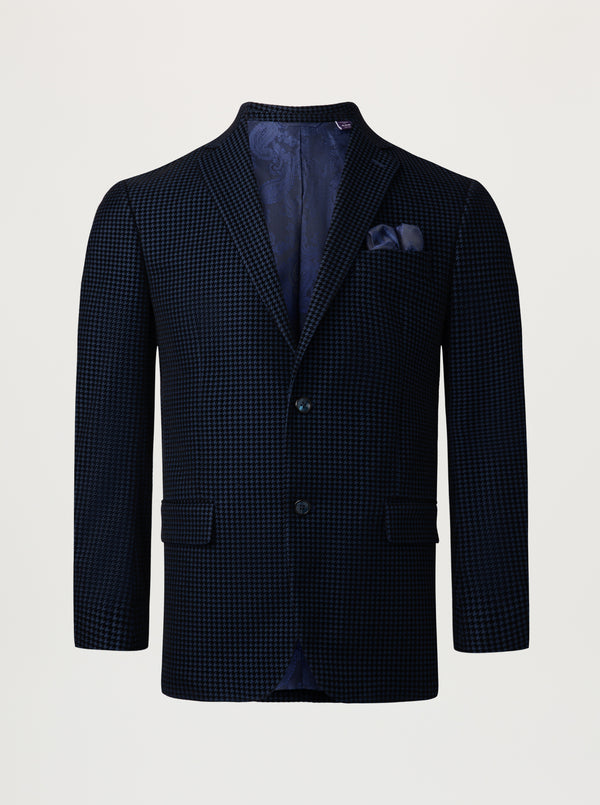 A dark navy blue single-breasted blazer with a fine micro-check pattern, featuring a matching pocket square, displayed on a neutral light gray background.