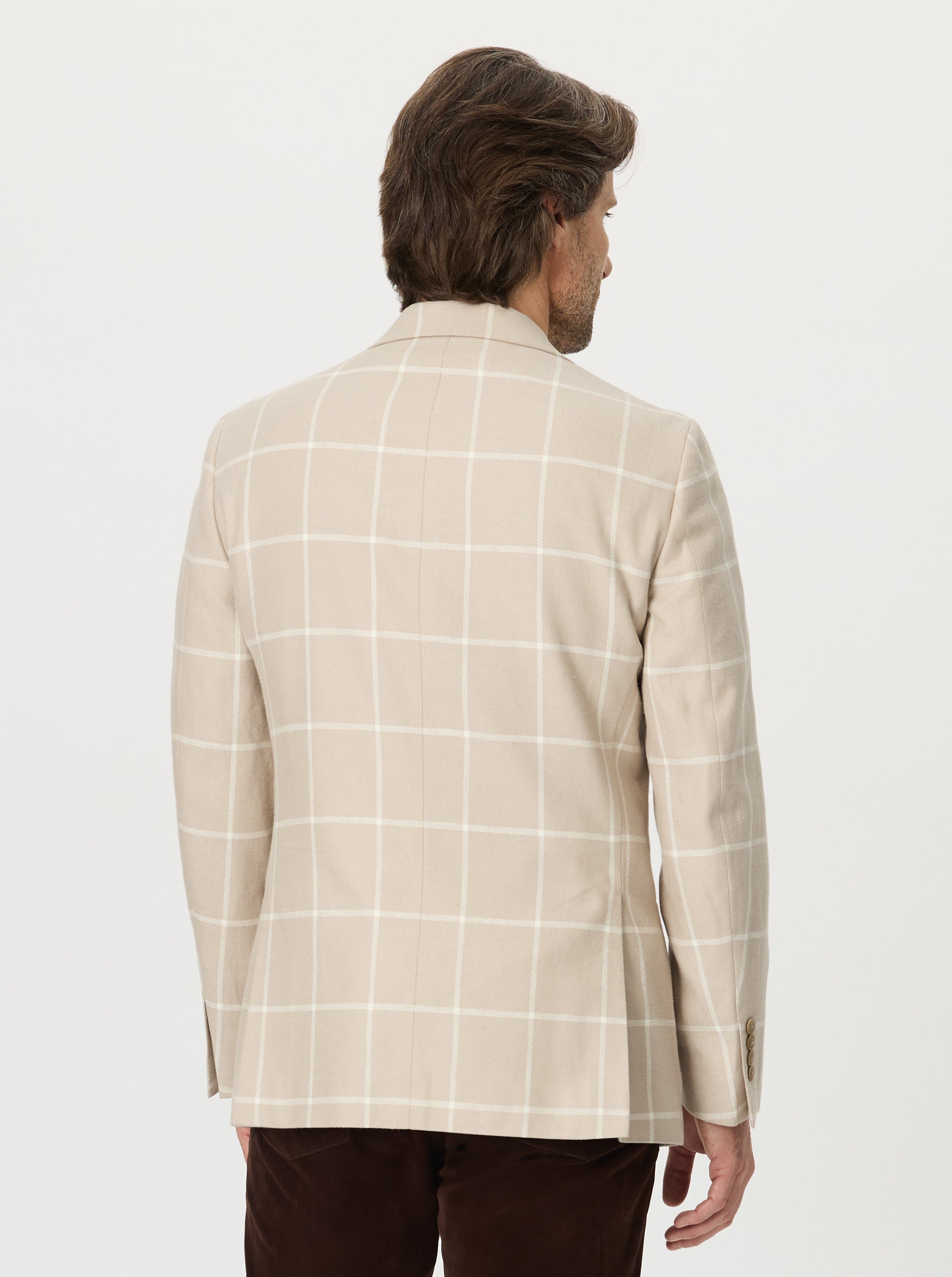 Man wearing a beige checkered blazer on a white background