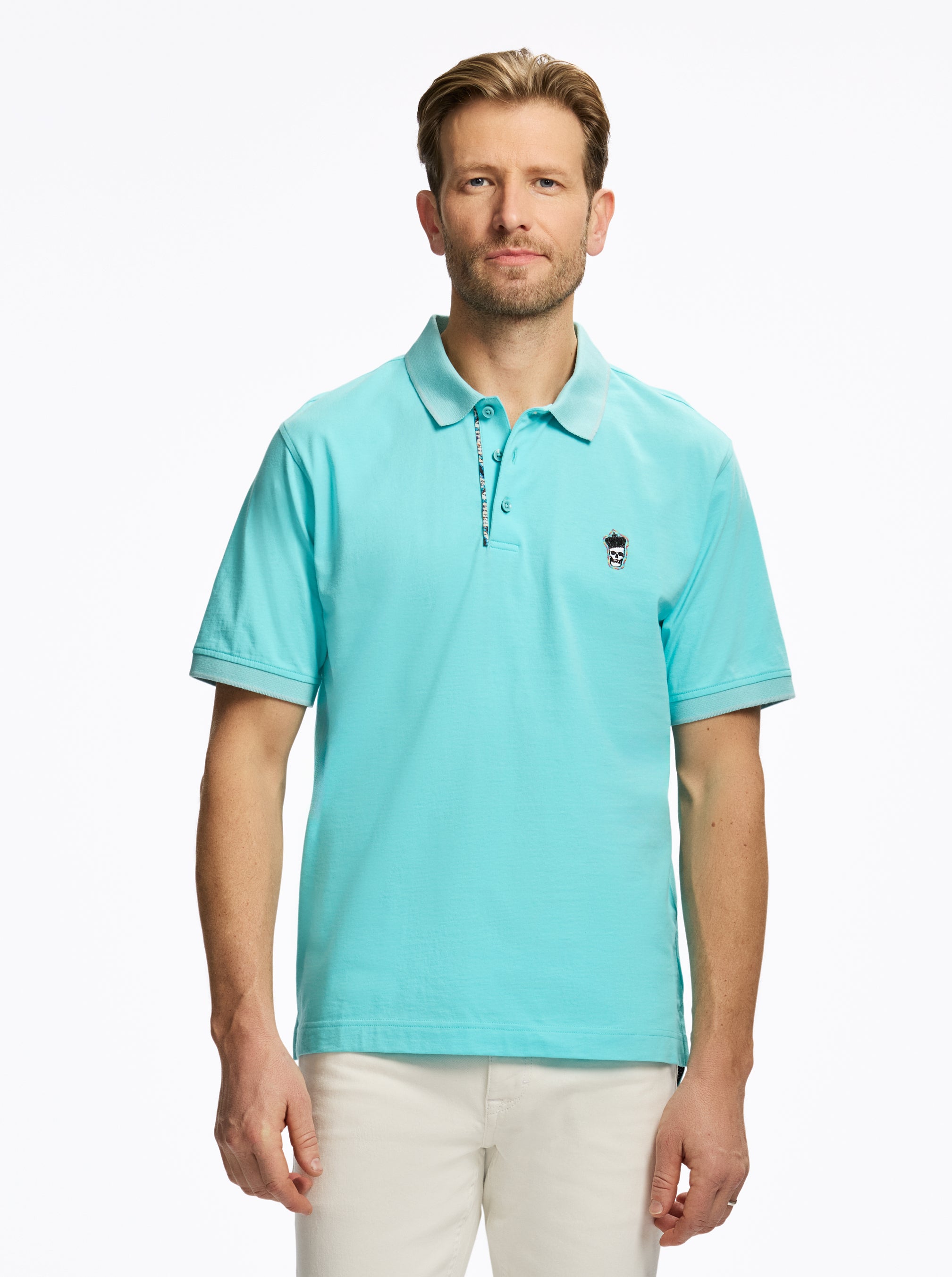 Man wearing a light blue polo shirt with a small logo on a white background