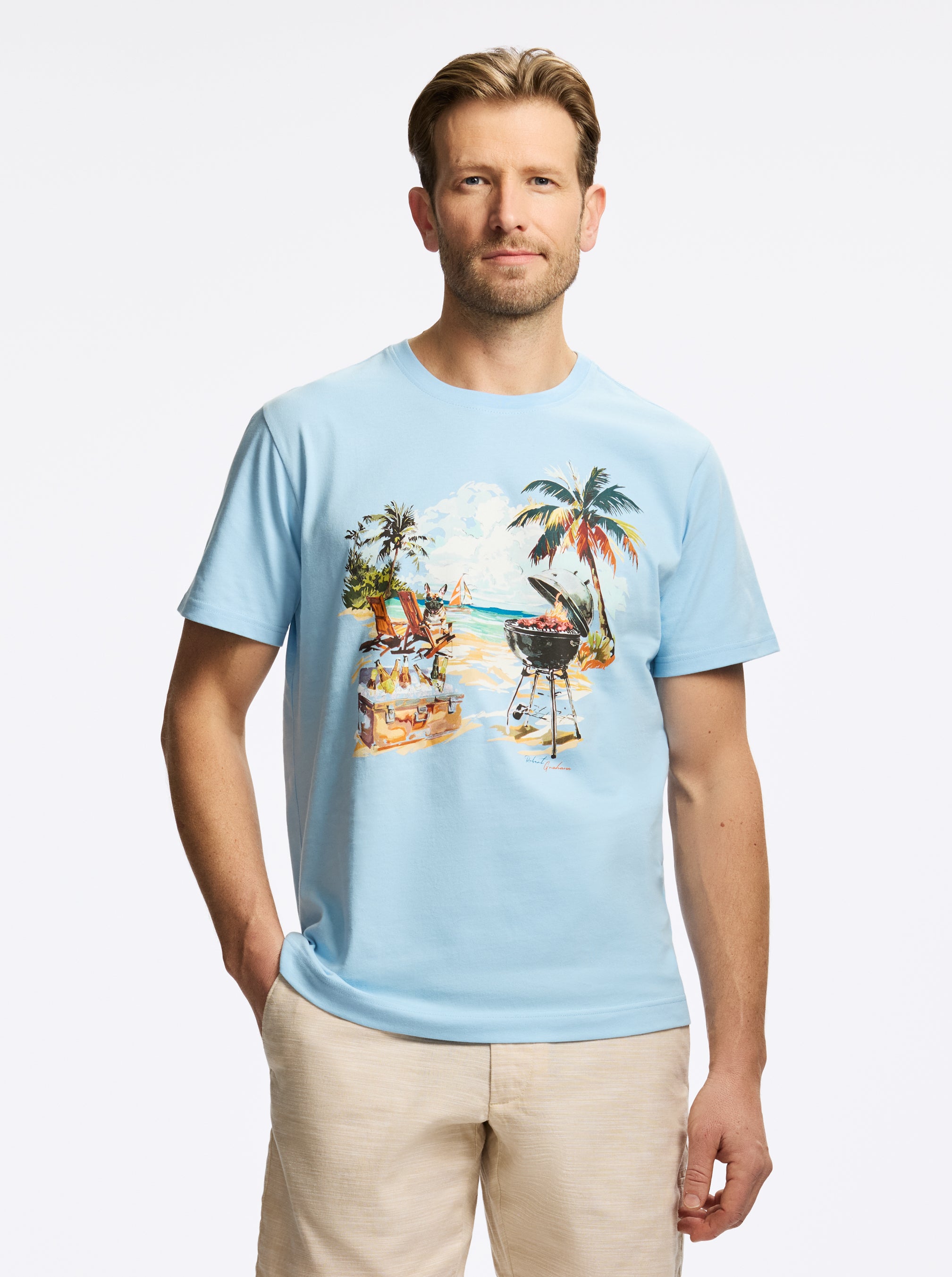 Man wearing a light blue t-shirt with a beach graphic on a white background