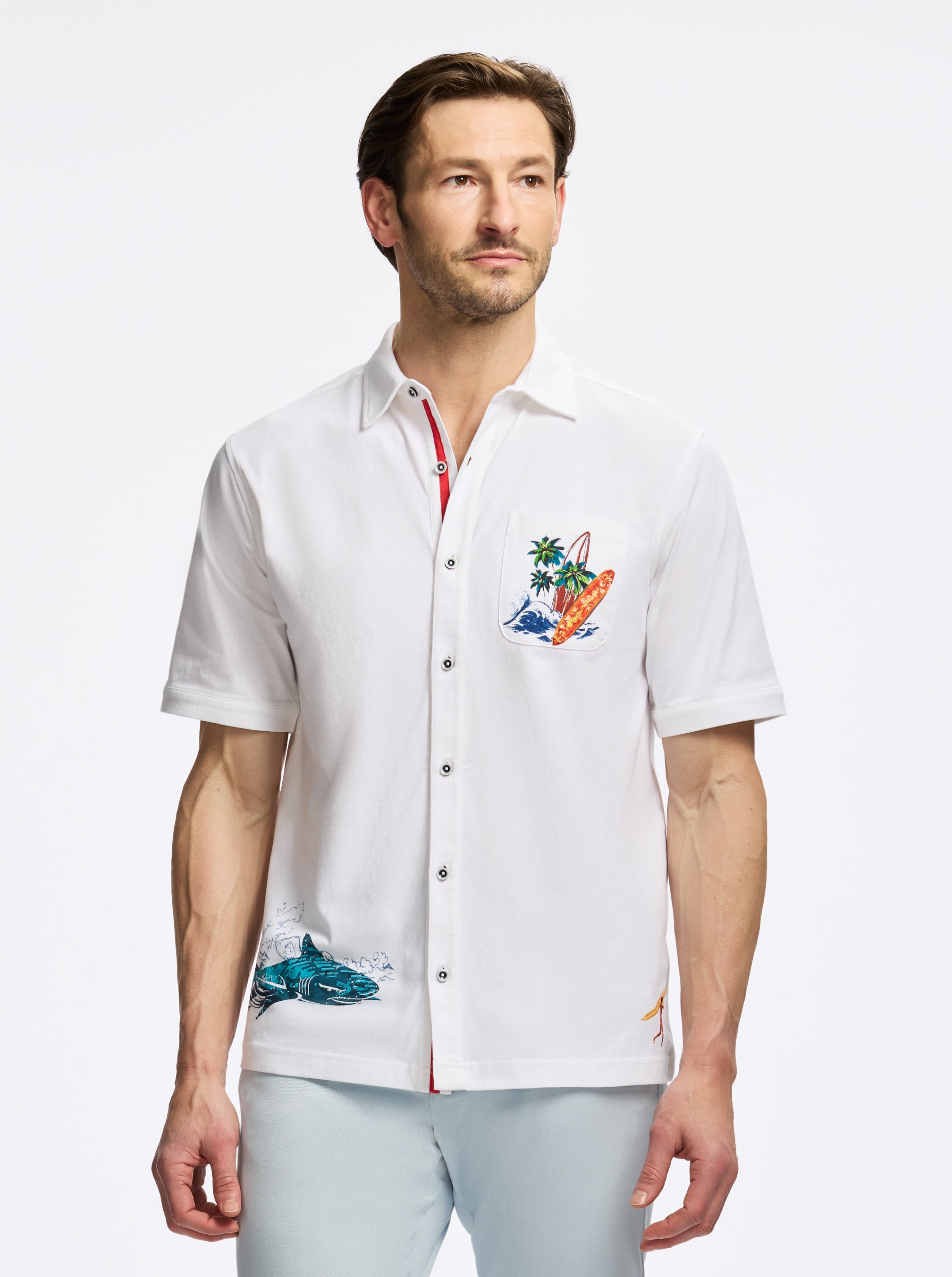 Man wearing a white short-sleeve shirt with colorful designs on a white background