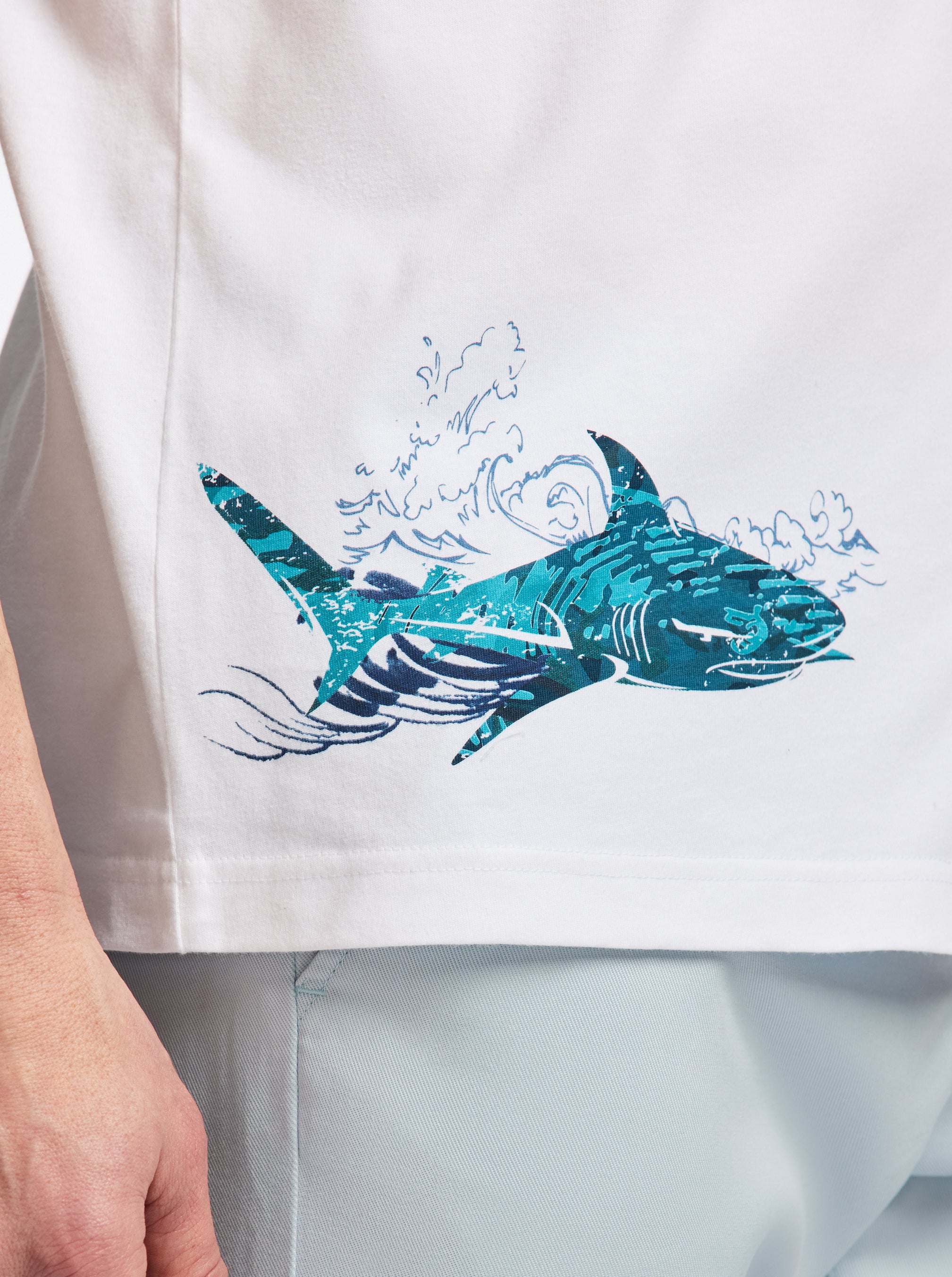 White shirt with a blue shark design on a white background