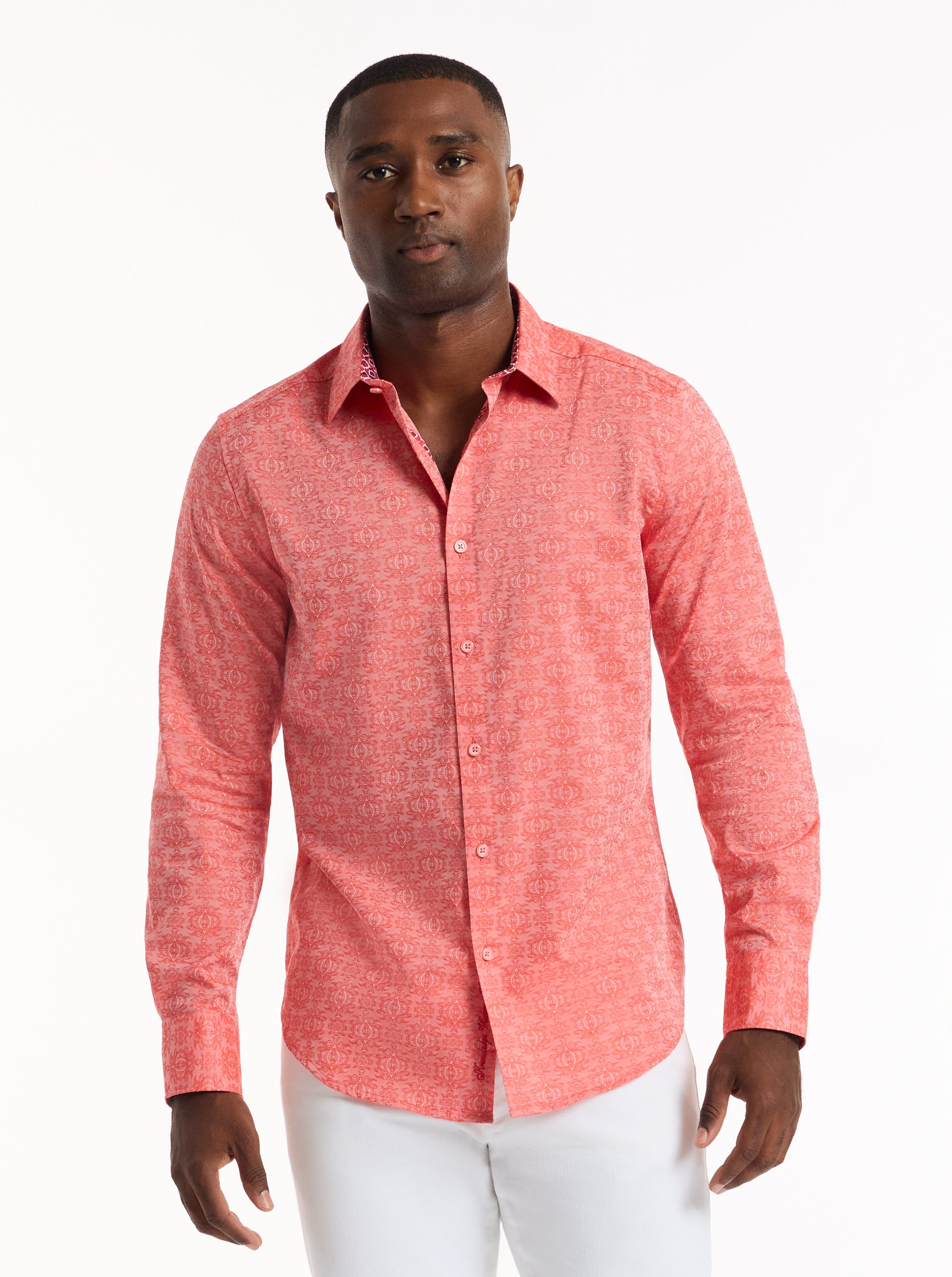 Man wearing a coral pink patterned shirt on a white background