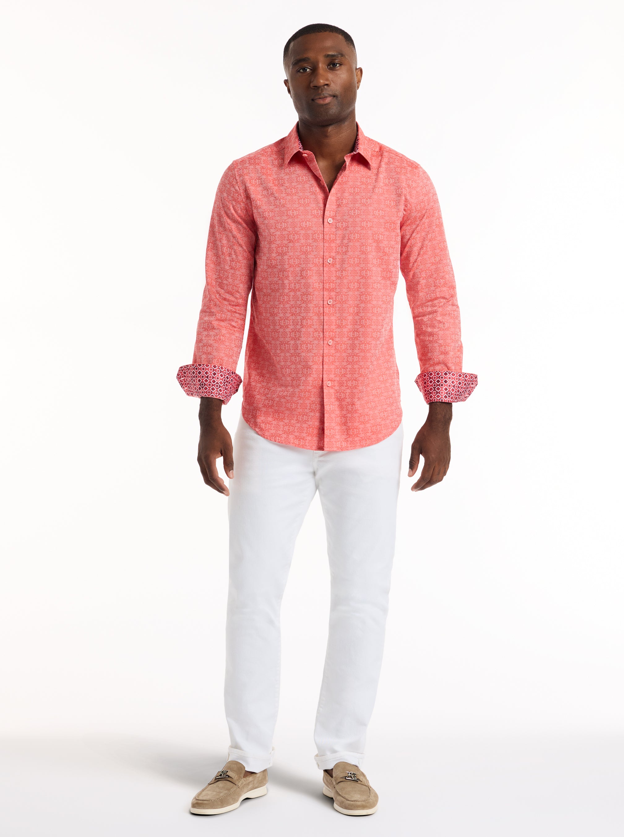 Man wearing a coral pink shirt and white pants on a white background