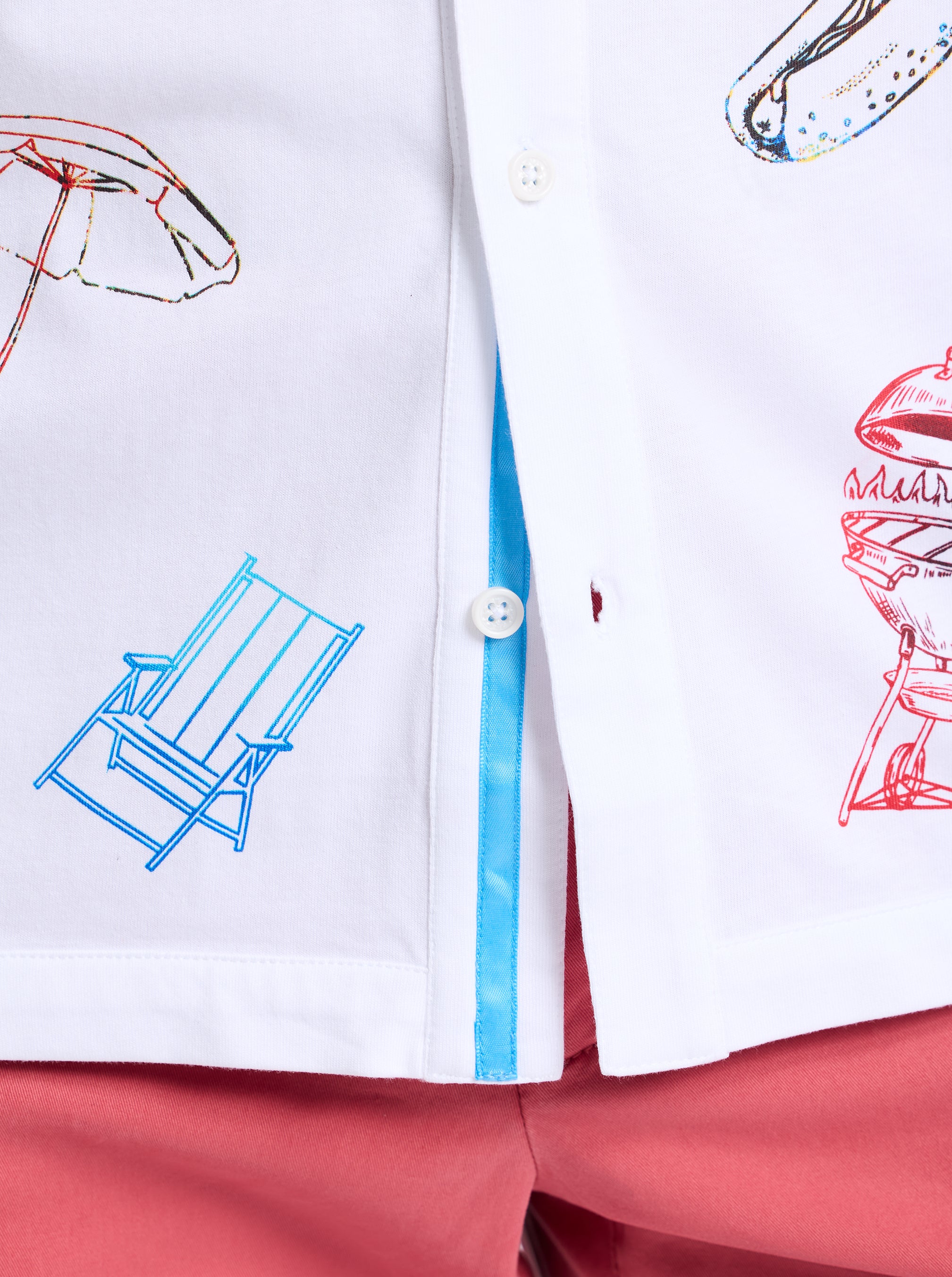 White shirt with colorful graphics of a deck chair, umbrella, and other items on a white background.