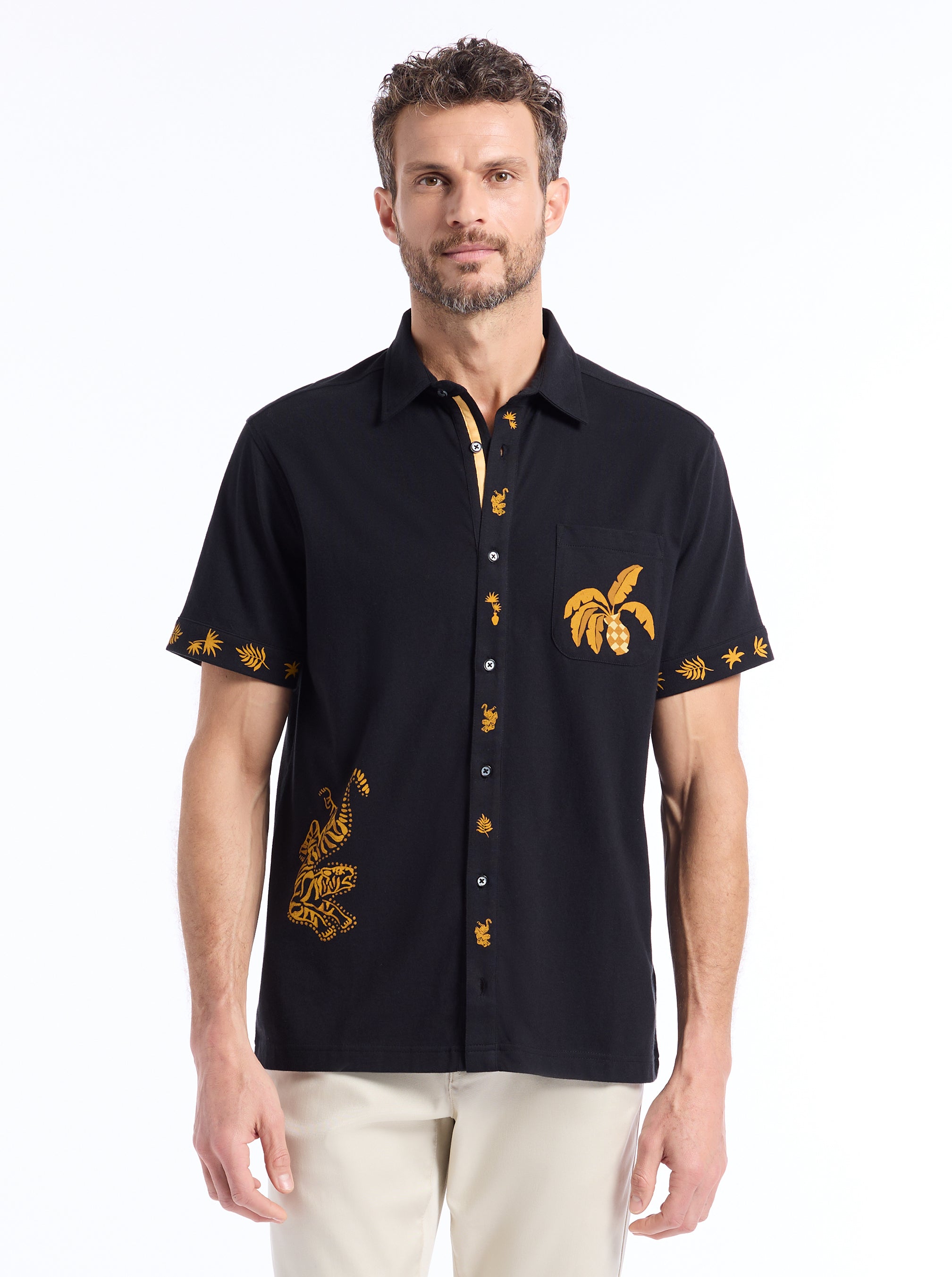 Man wearing a black shirt with gold embroidery on a white background