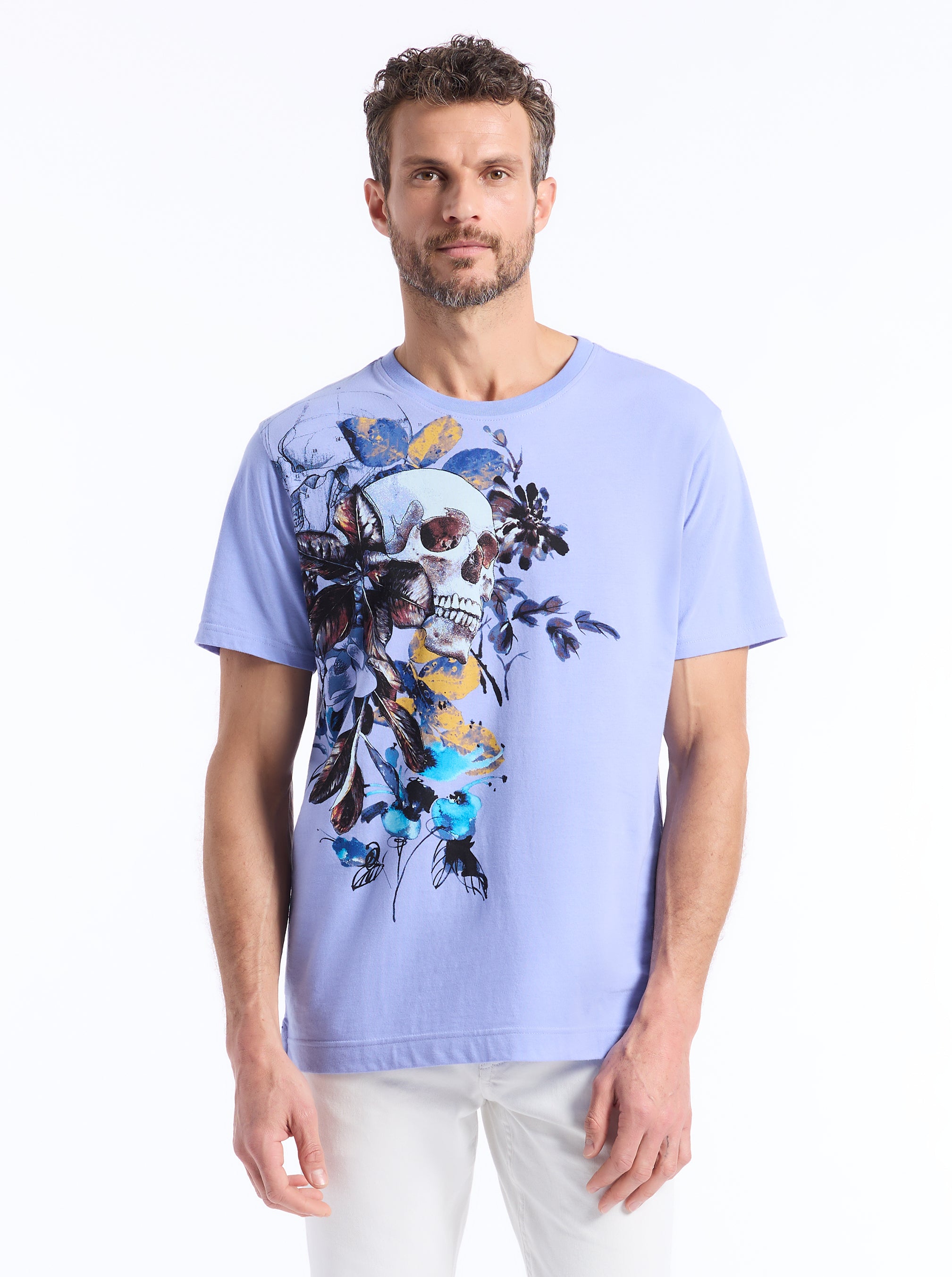 Man wearing a light blue t-shirt with a colorful skull and floral design on a white background
