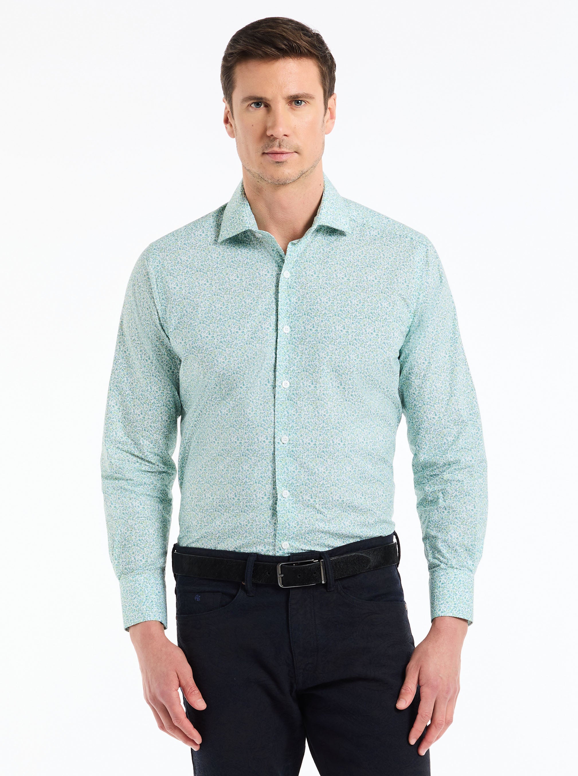Man wearing a light blue patterned shirt and dark pants on a white background