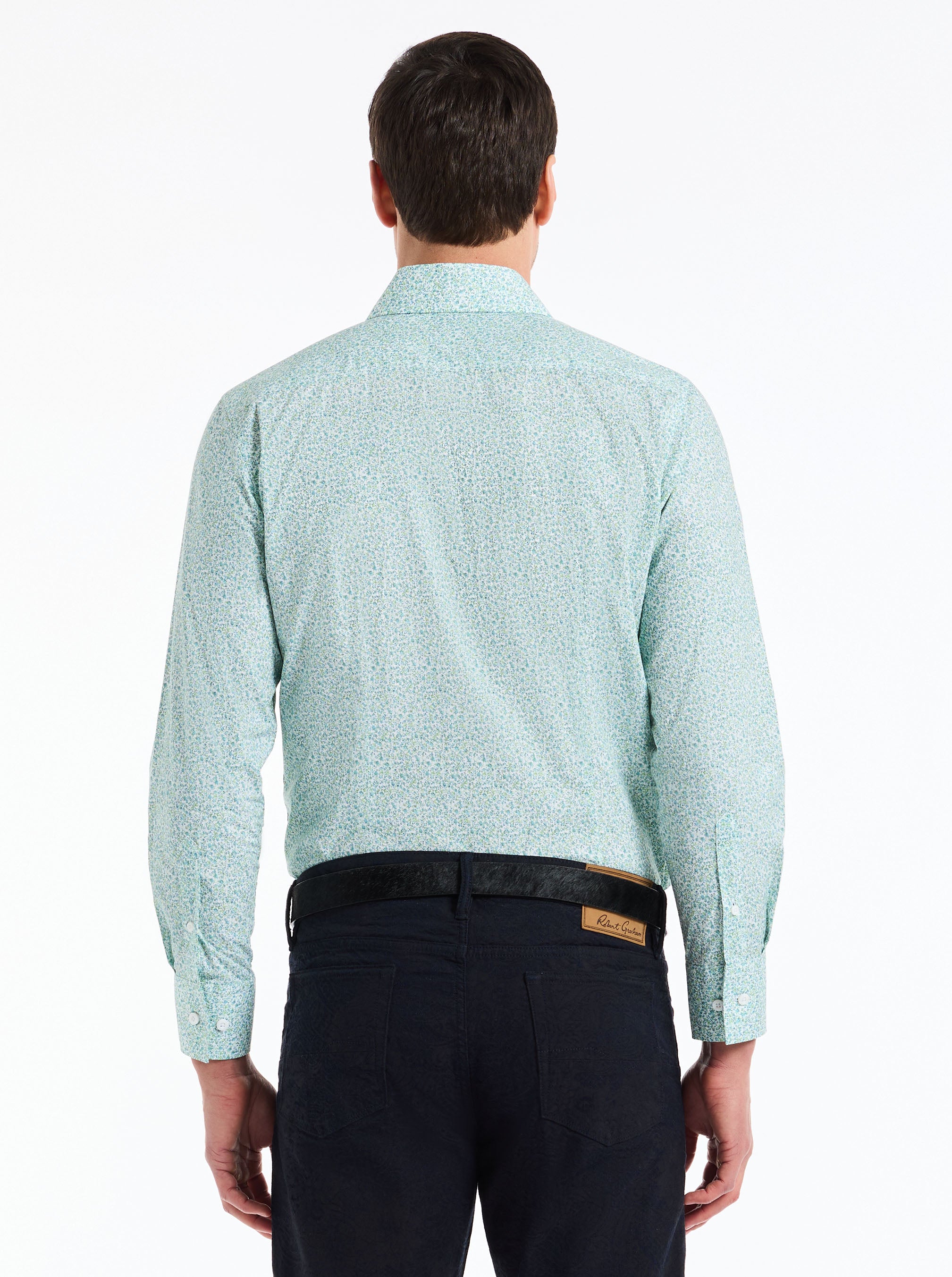 Man wearing a light blue patterned shirt and dark pants on a white background