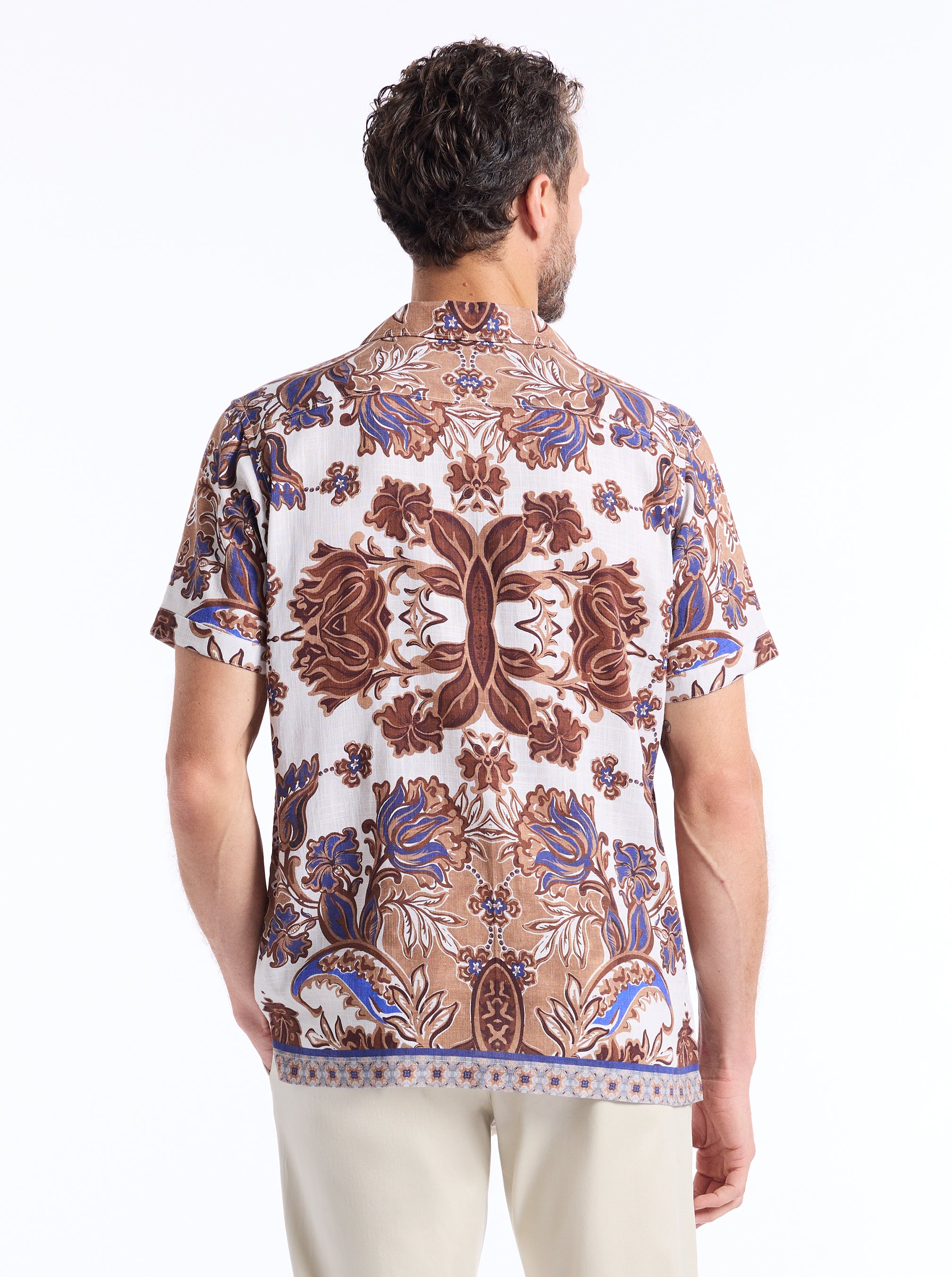 Man wearing a ornate and floral  patterned shirt on a white background